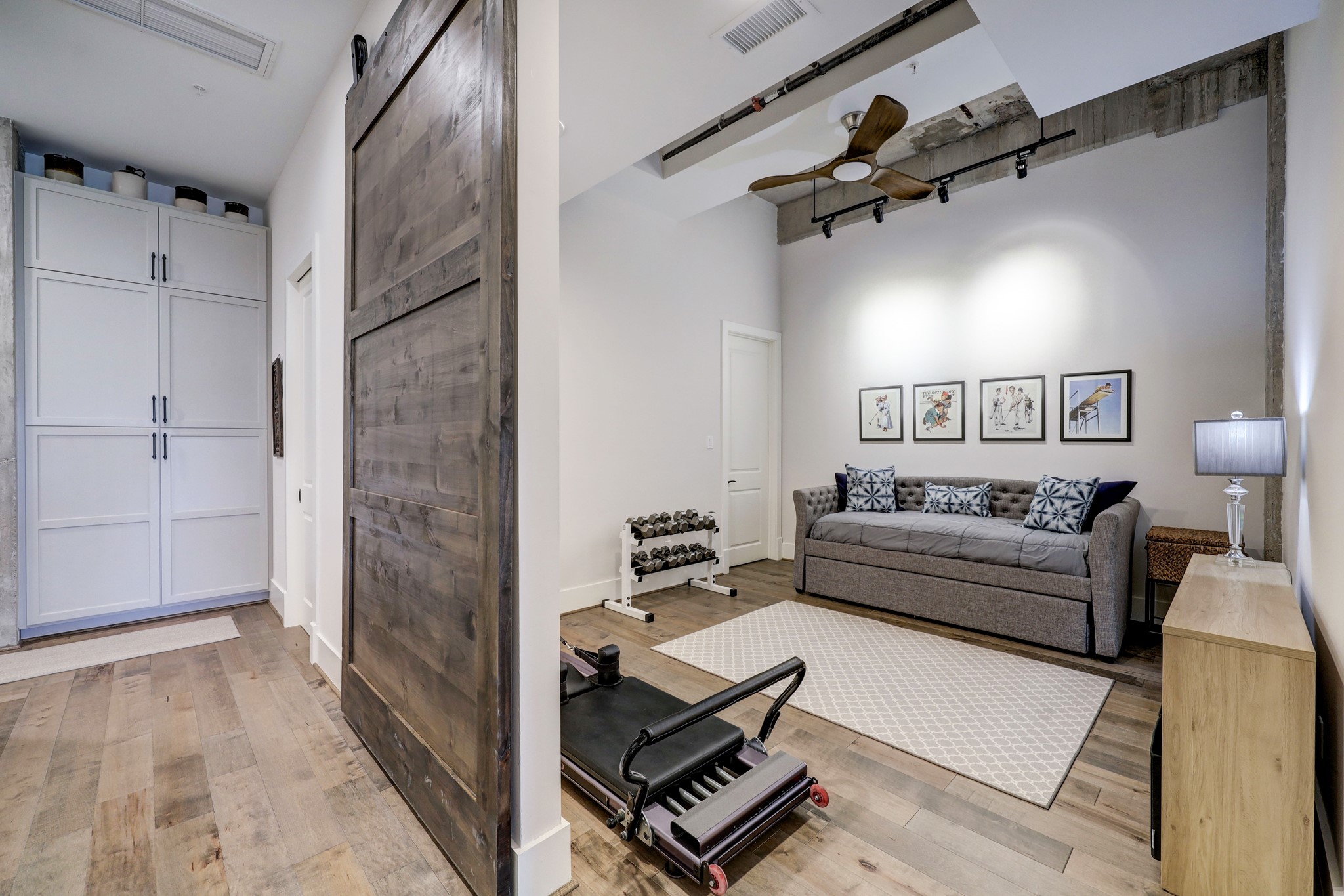 An attractive barn door leads you into the secondary bedroom which features an exposed original concrete beam, engineered hardwood floors, lighting and ceiling fan.