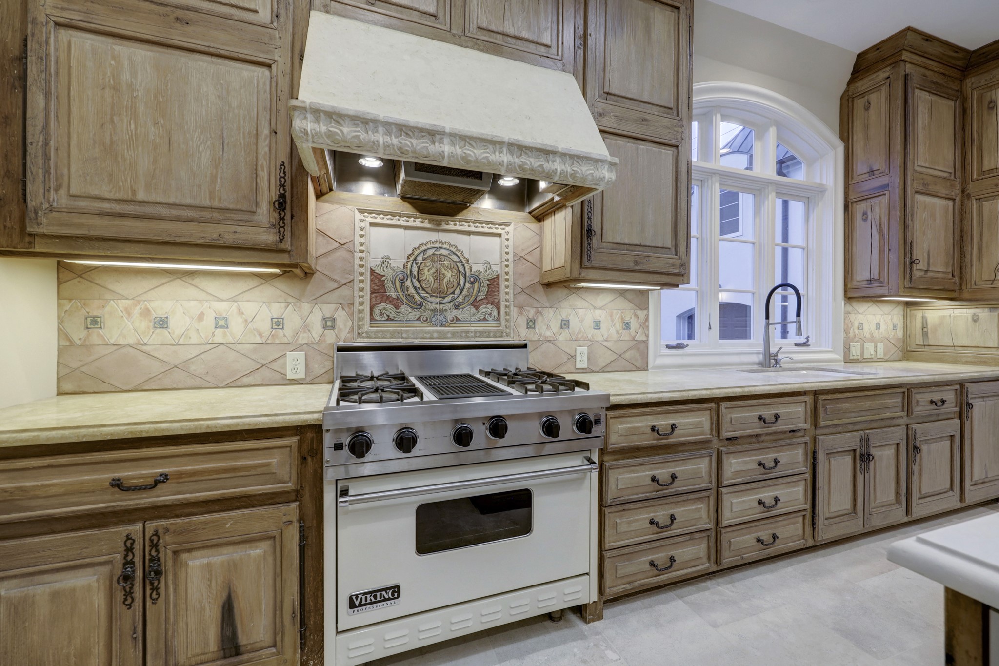 The VIKING Professional series range boasts 4-burners and grill with professional series vent hood.  Note the decorative backsplash and rustic French Chateau style cabinets.  What a beautiful place to create not only meals, but memories too!