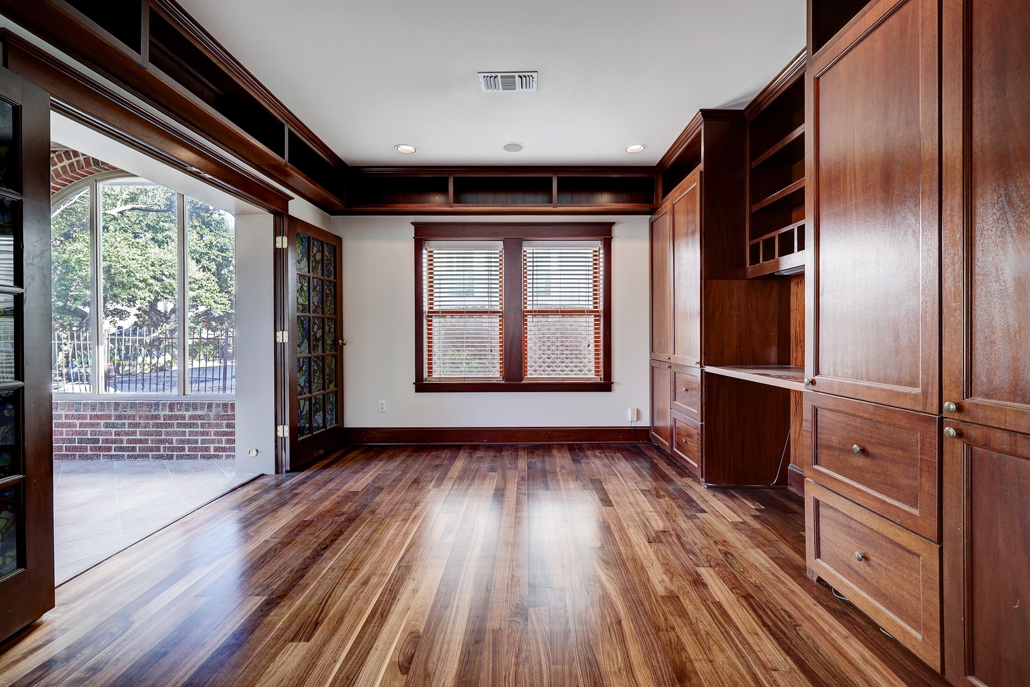 To the left of the formal living sits the private library which is complete with custom built-in cabinetry, recessed lighting, and stained glass French doors that lead you to the home’s sunroom.