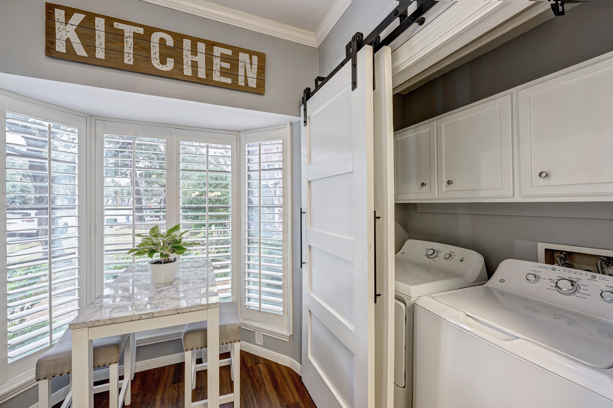 With tasteful plantation shutters and a warm ambience, the breakfast room in the kitchen offers a cozy atmosphere. Meanwhile, the laundry closet/room can be found behind the double doors to the right.
