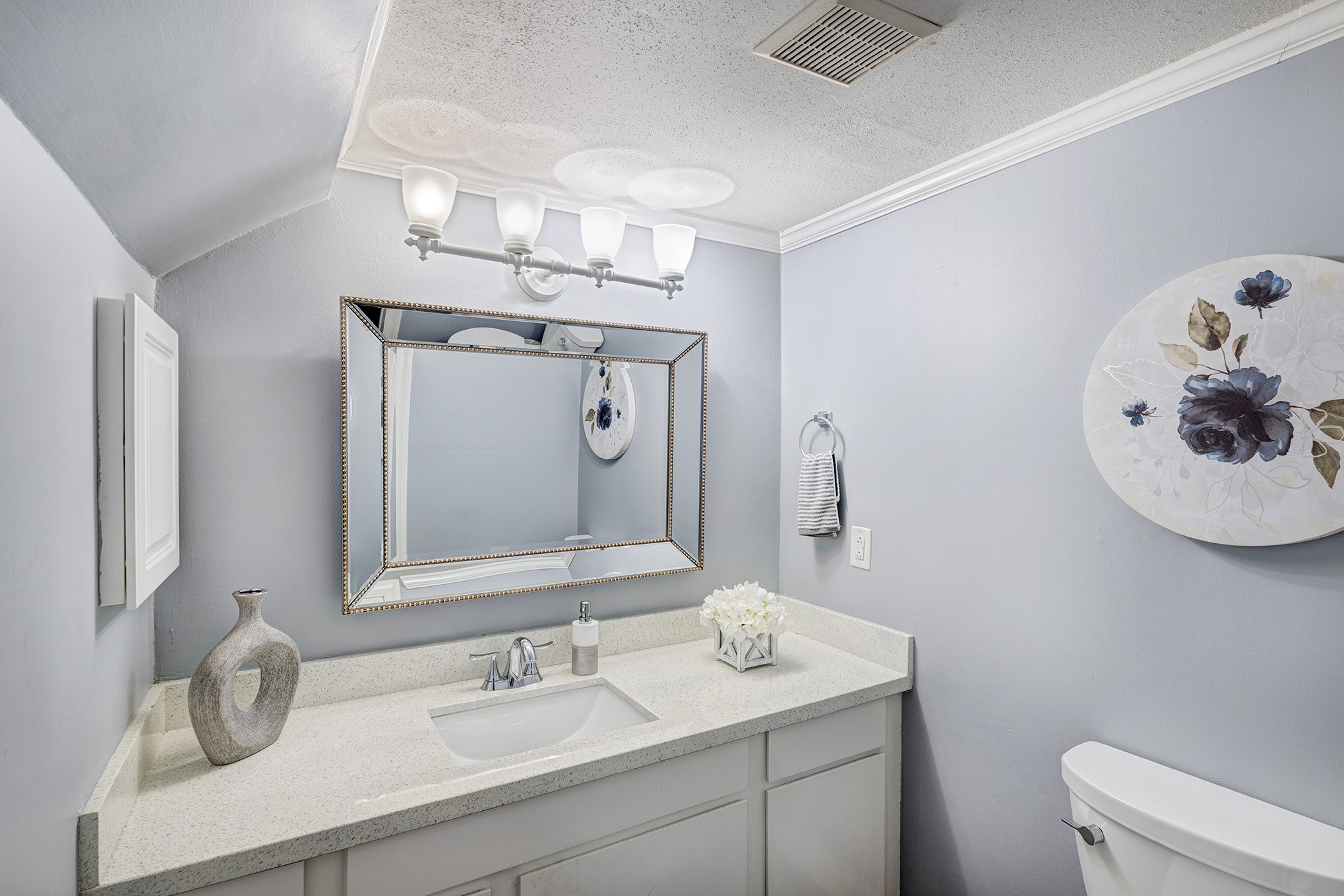 Located on the first floor just off the kitchen is a chic powder bath with a furniture-piece vanity and sconce lighting above.