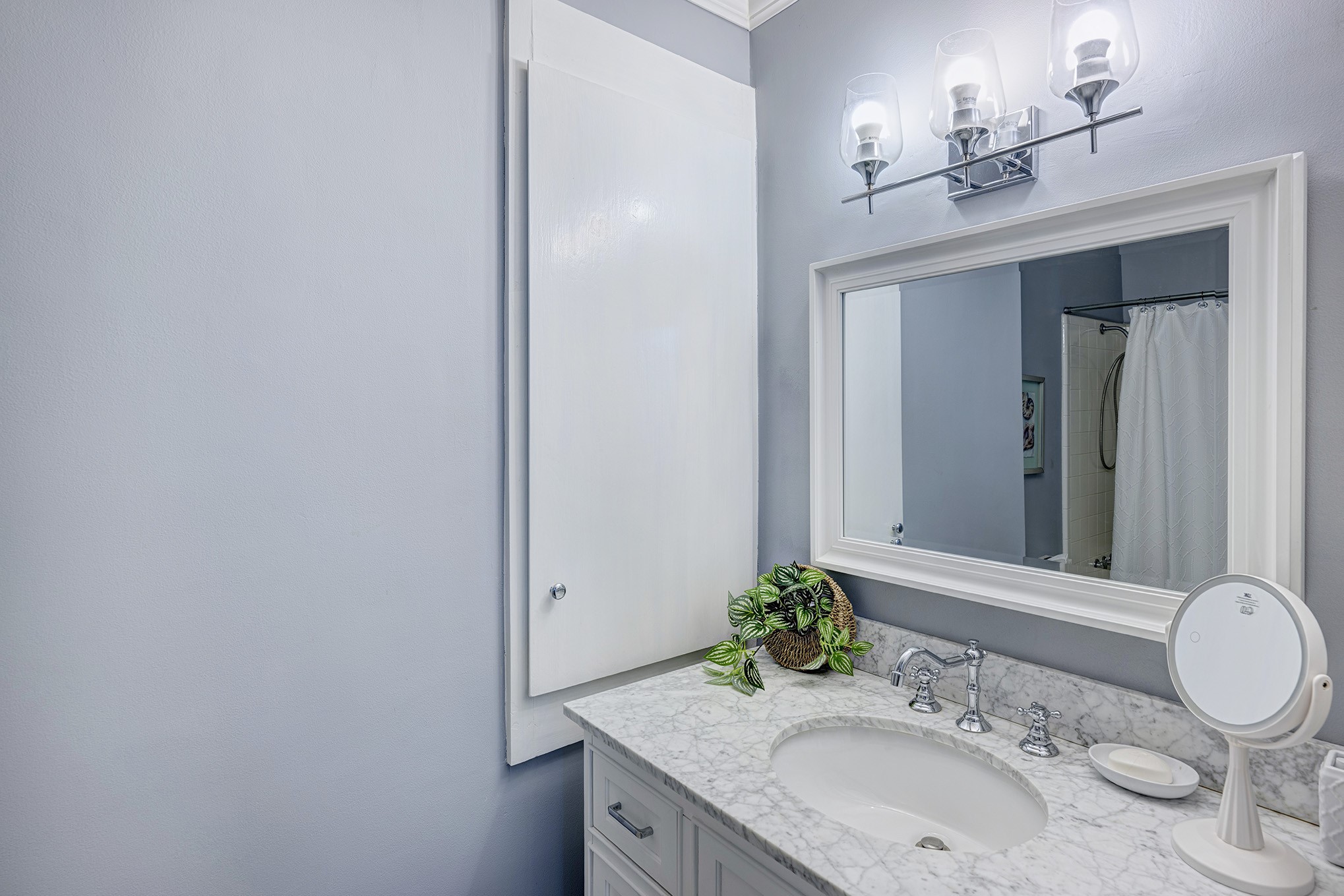The recently acquired stand-alone vanity is equipped with soft-close drawers and adorned with a Carrera marble countertop, accentuated by an oval under mount sink complemented by a sleek chrome faucet. A capacious in-wall linen closet and a medicine cabinet cater to the storage needs of the bathroom.