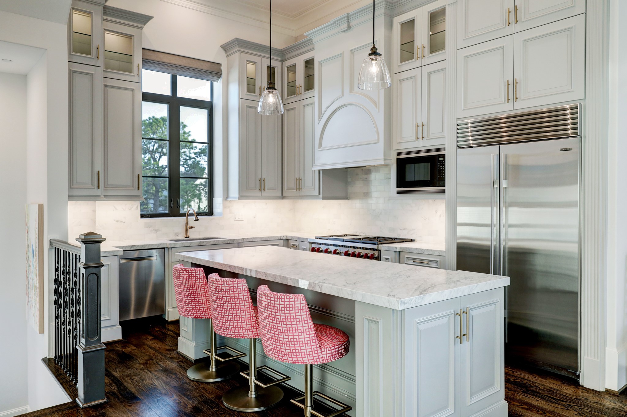 The kitchen features glass front cabinets, soft-close cabinets and drawers and marble countertops and backsplash.