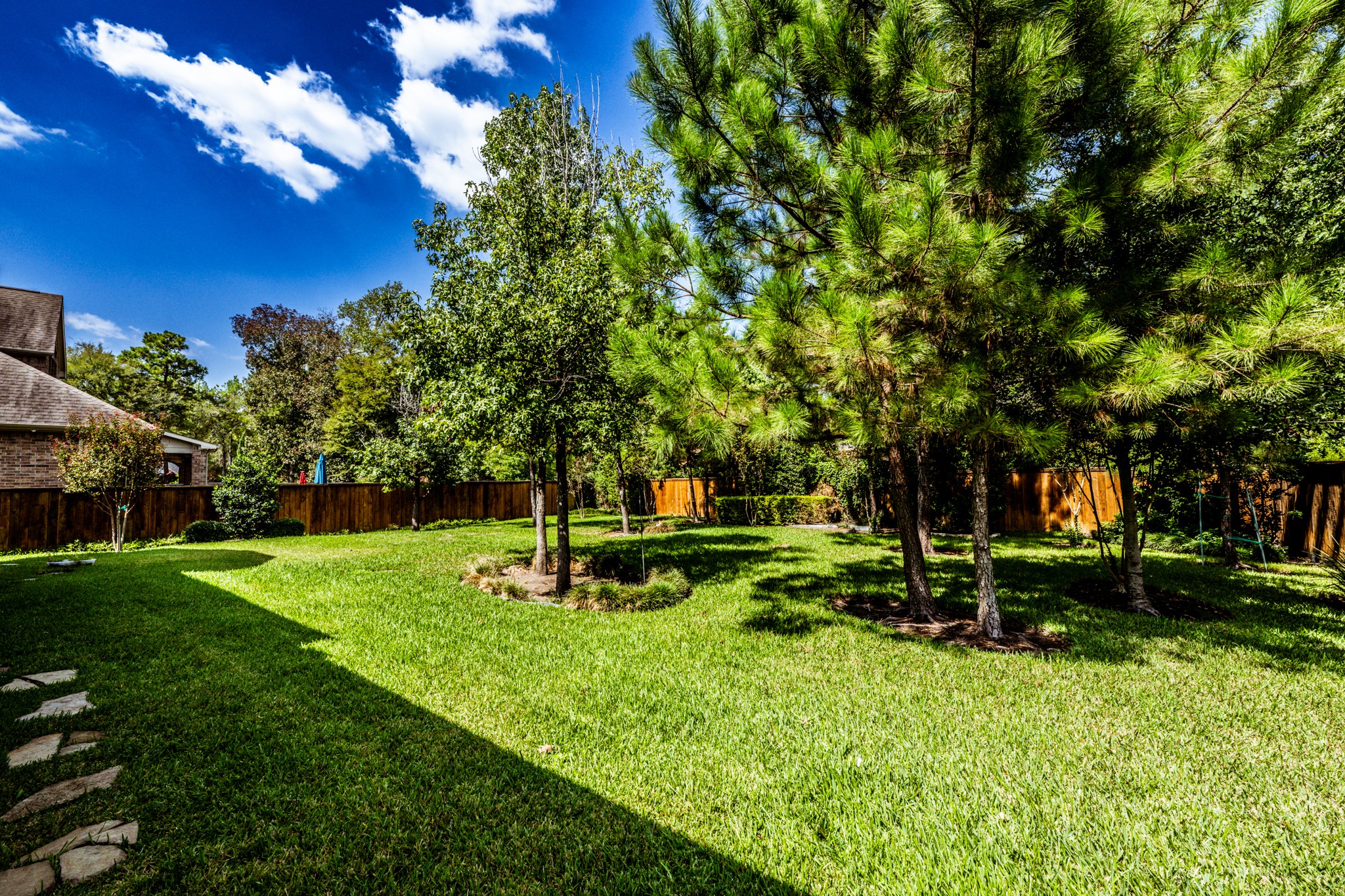 Large backyard with trees providing ample shade.