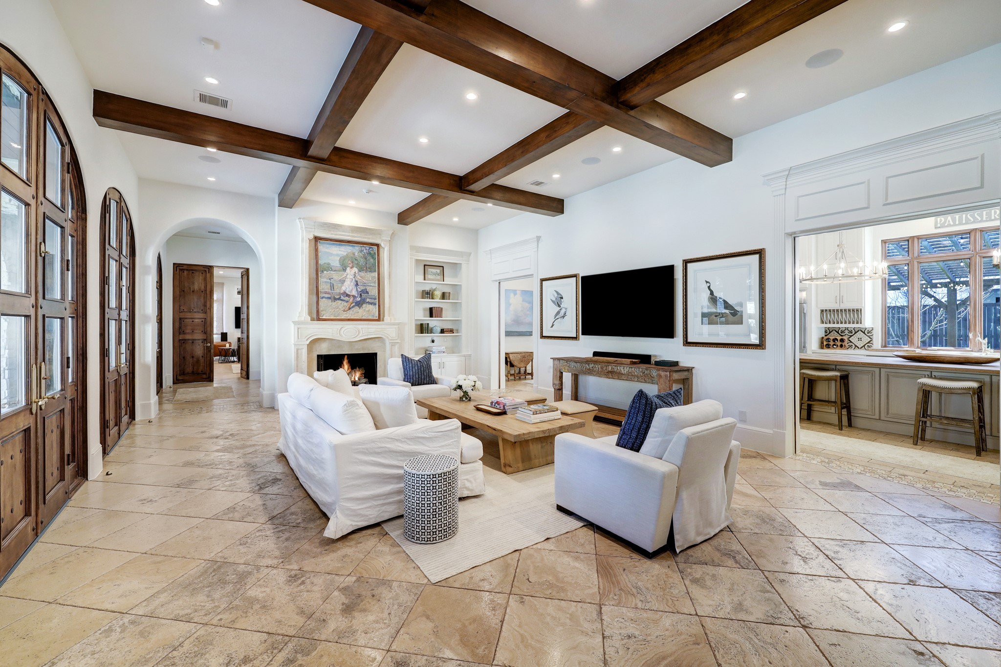 With a central location and impressive 12-foot ceilings, this space is enhanced by operable French doors that open up to the pool area. It also showcases convenient built-in bookcases, ceiling speakers, and elegant limestone floors.