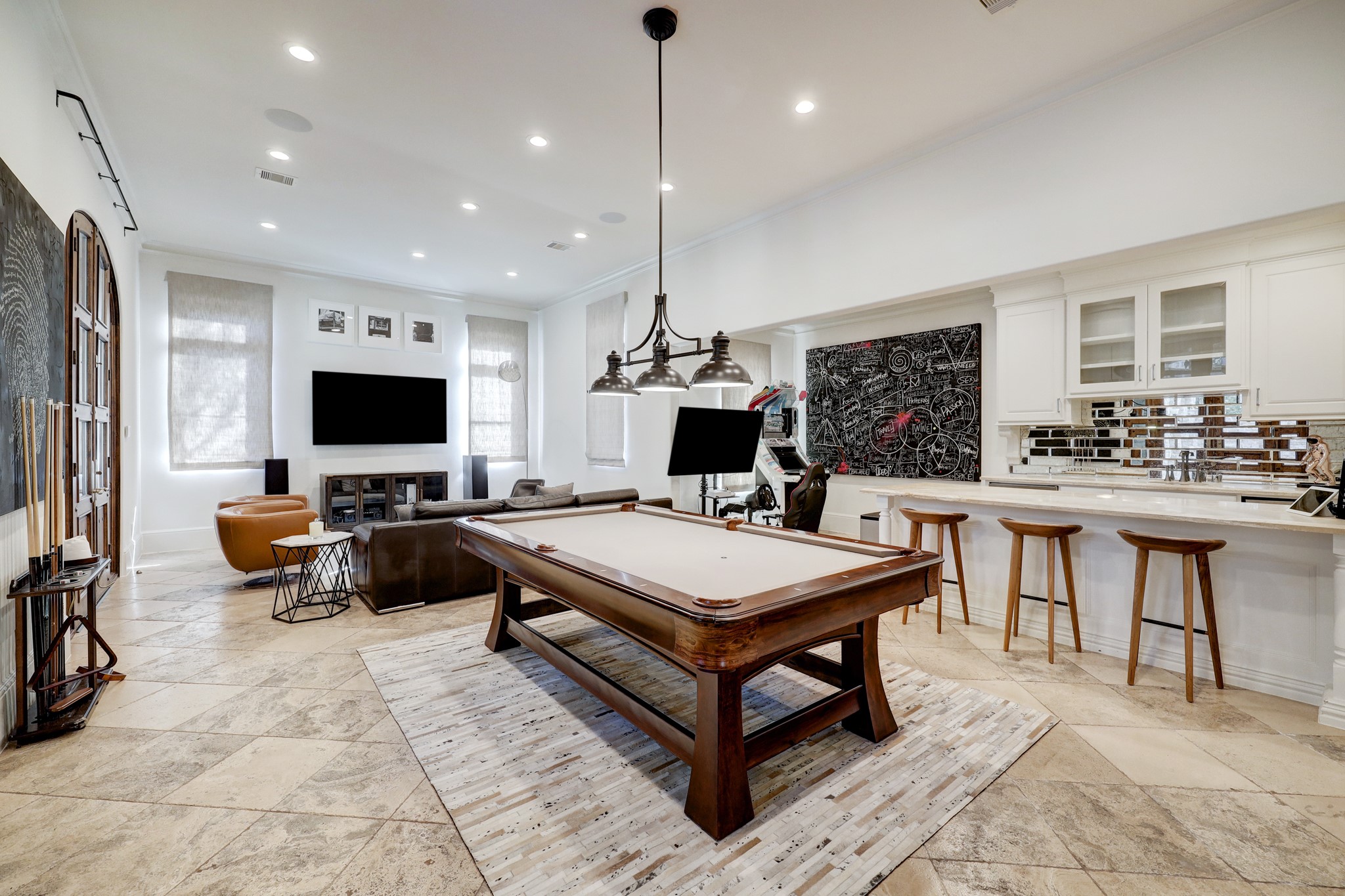 The entertainment room offers a captivating view that showcases its direct access to the summer kitchen and windows overlooking the rear driveway. This layout allows for easy flow between indoor and outdoor entertaining spaces.
