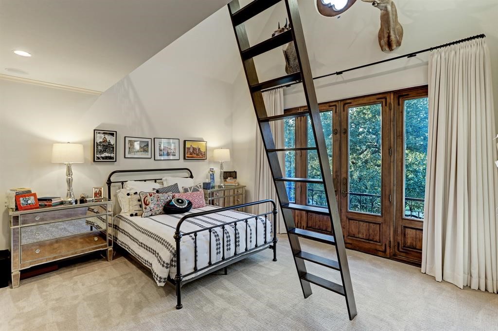  This secondary bedroom also includes a charming Juliet balcony, a spacious walk-in closet, and an en-suite bath for added convenience and privacy. Moreover, the room features a loft area furnished with bookcases and a safety rail, adding a touch of functionality and style to the space.