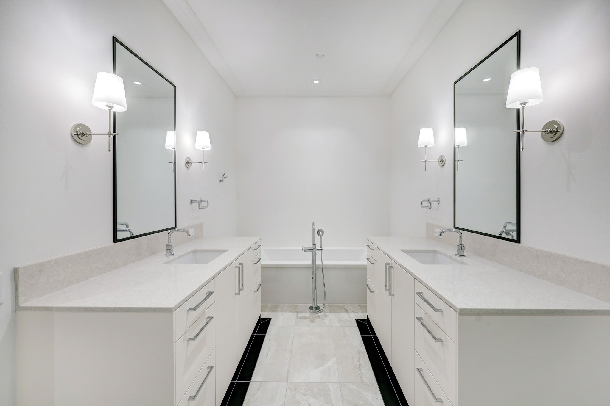 This primary bathroom is well laid out and complete with luxury finishes and symmetrical dual vanities framed by an expanse of rich quartz. A statement making soaking tub anchors the space with a feature art wall above.