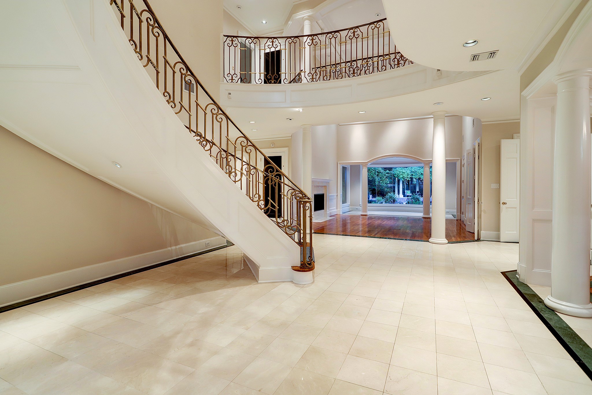 Foyer opens to the two-story living room with a view of the lushly landscaped back yard and pool.