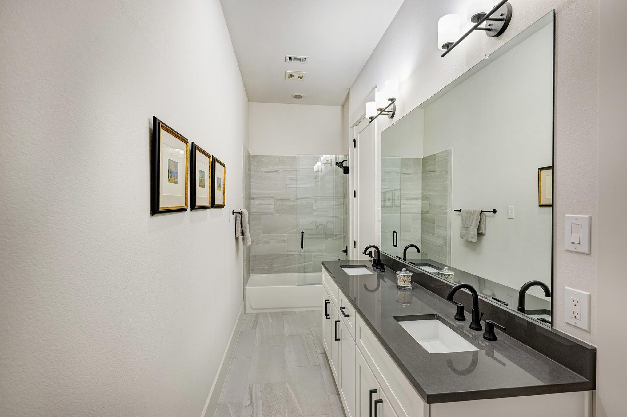 Hallway bathroom can be accessed from the hallway or the back secondary bedroom. Dual sinks, quartz counter, shower/tub and private water closet.