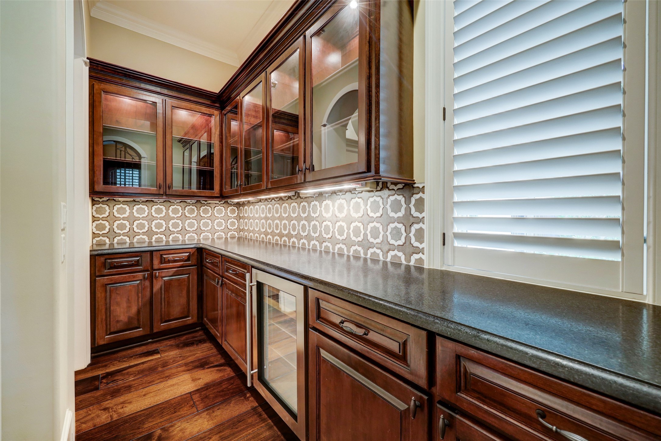 Your butler will love this Butler's Pantry! Above are lighted cabinets with glass shelves.  Below is a Beverage Chiller with drawers and cabinets.  In between is an updated backsplash.