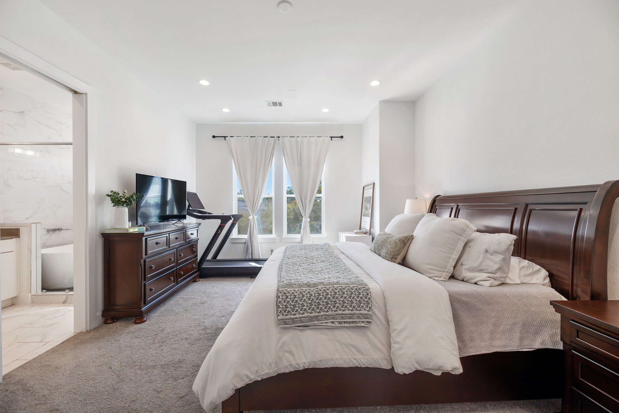 As you reach the third floor you are greeted by the luxurious primary suite.  The bedroom has large windows, electronic shades + a beautiful retreat style bath.