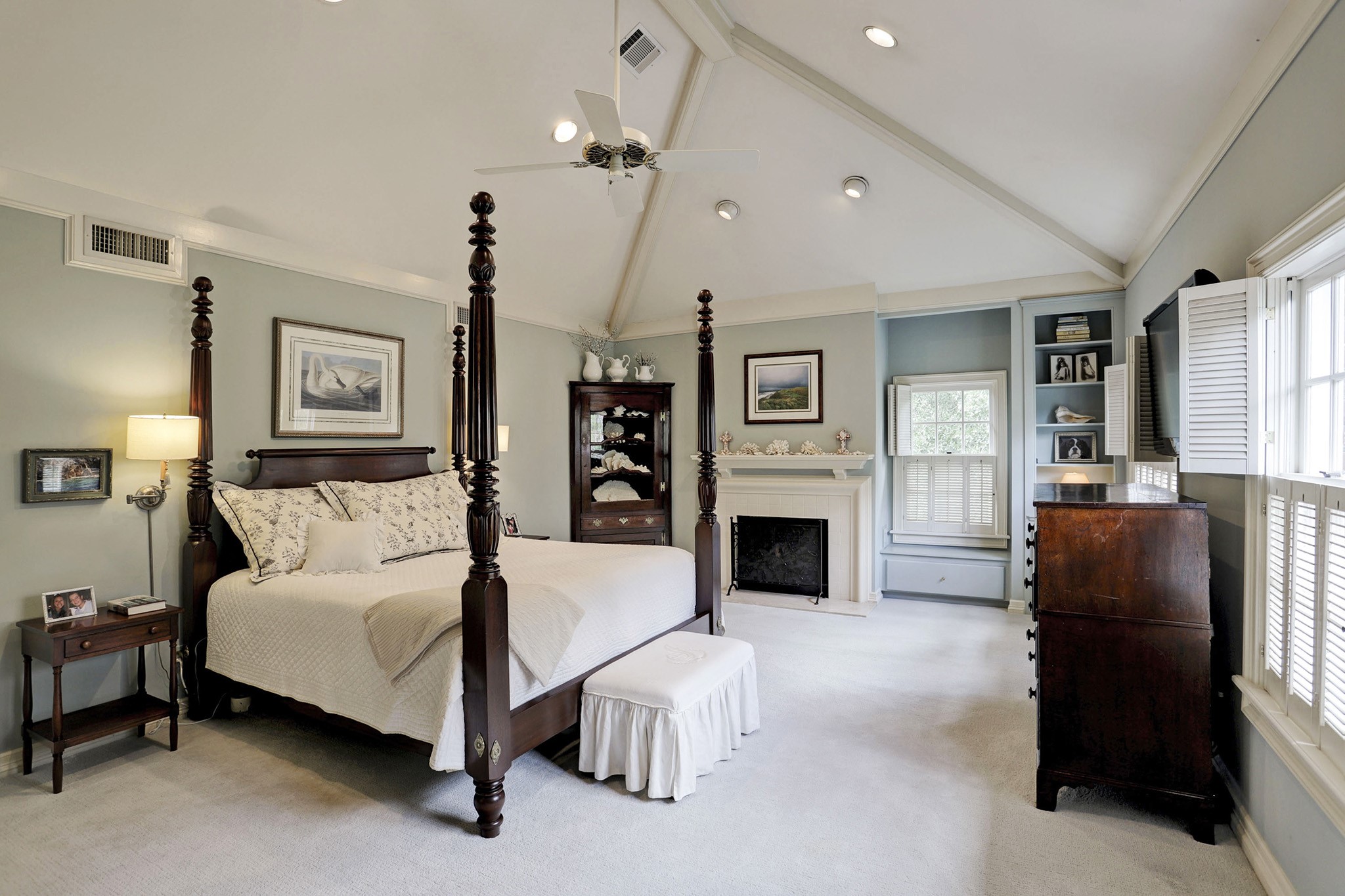 The primary bedroom features tall ceilings, a gas fireplace, and ample natural light.