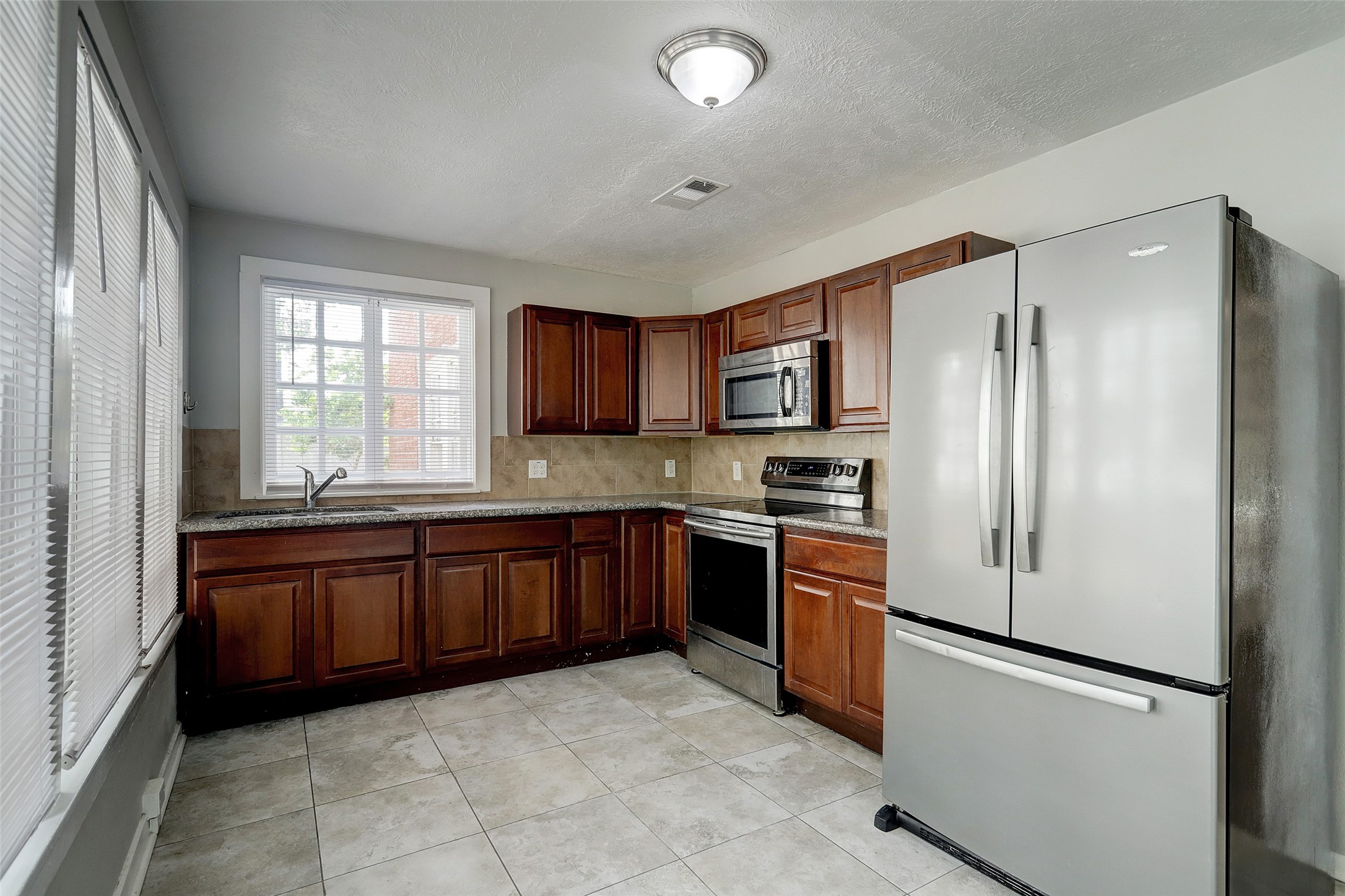 The kitchen features stainless steel appliances and looks out onto the backyard area and front porch. The walls are lined with windows for plenty of natural light.