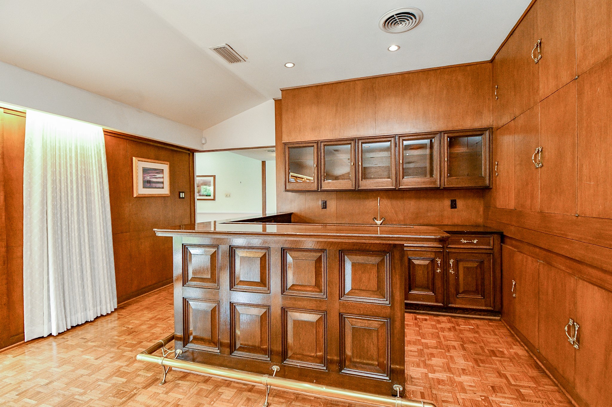 Full wet bar with icemaker is a part of the formal living area.  Note all the cabinets that surround the bar area. This is a beautiful real wood wet bar with a polished brass bar foot rain on both sides.