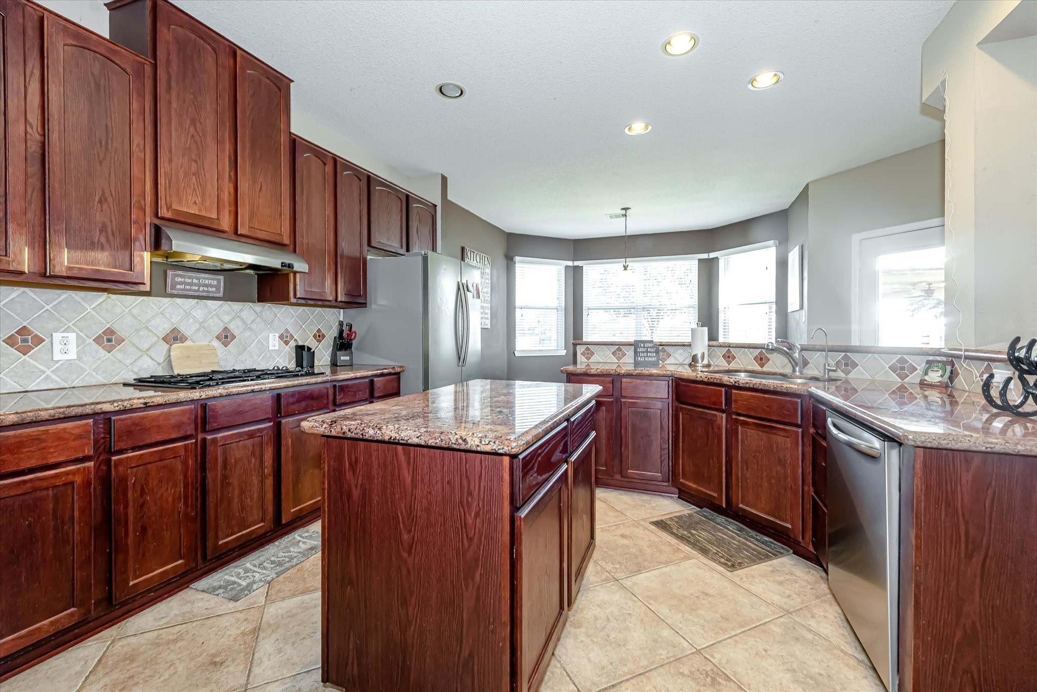 Island kitchen has tile floor, granite counters and tile backsplash.