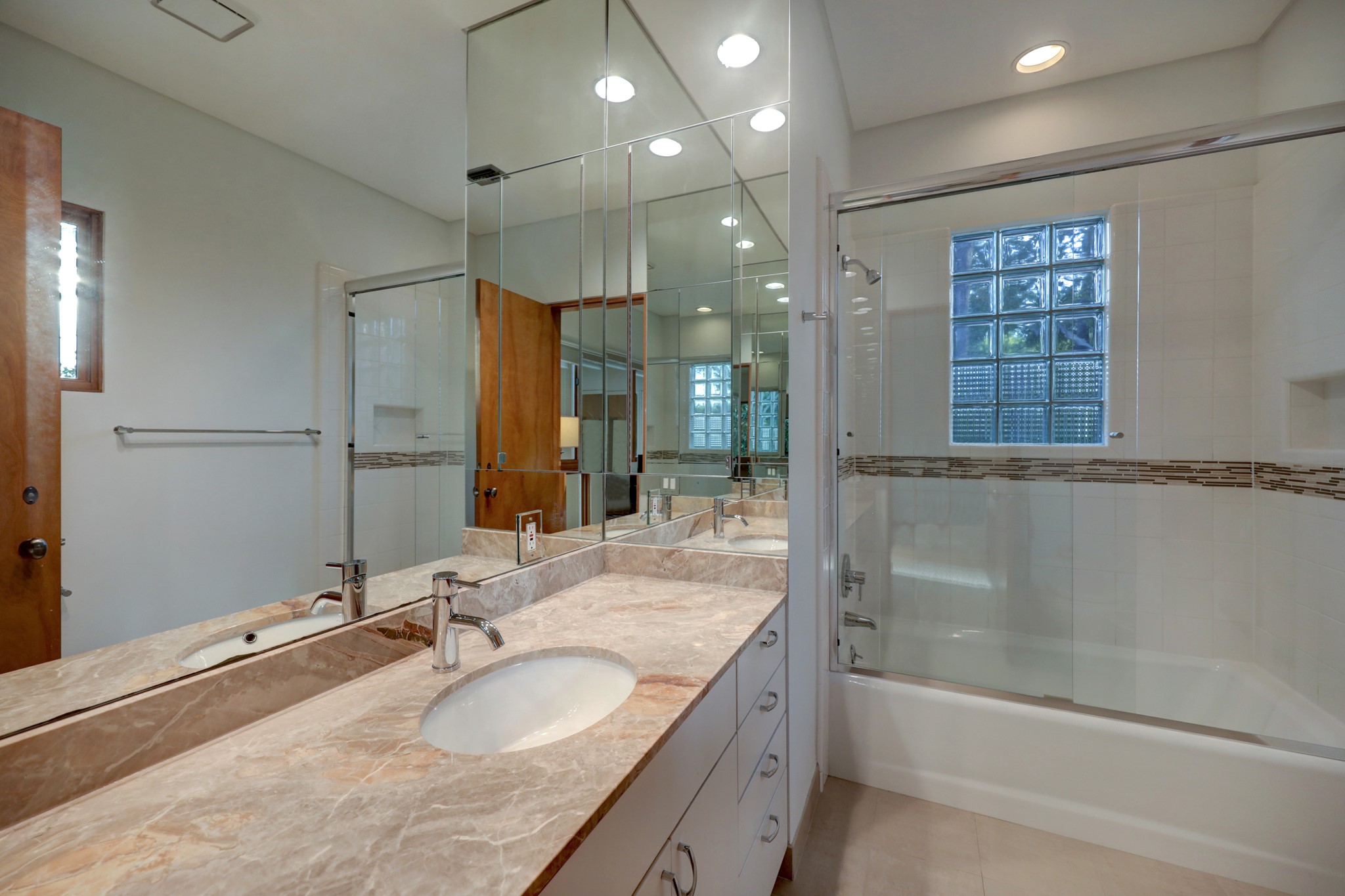 Second full ensuite bathroom features, marble countertop, custom cabinets, wall-to wall mirror, a shower-tub combination with a shampoo niche