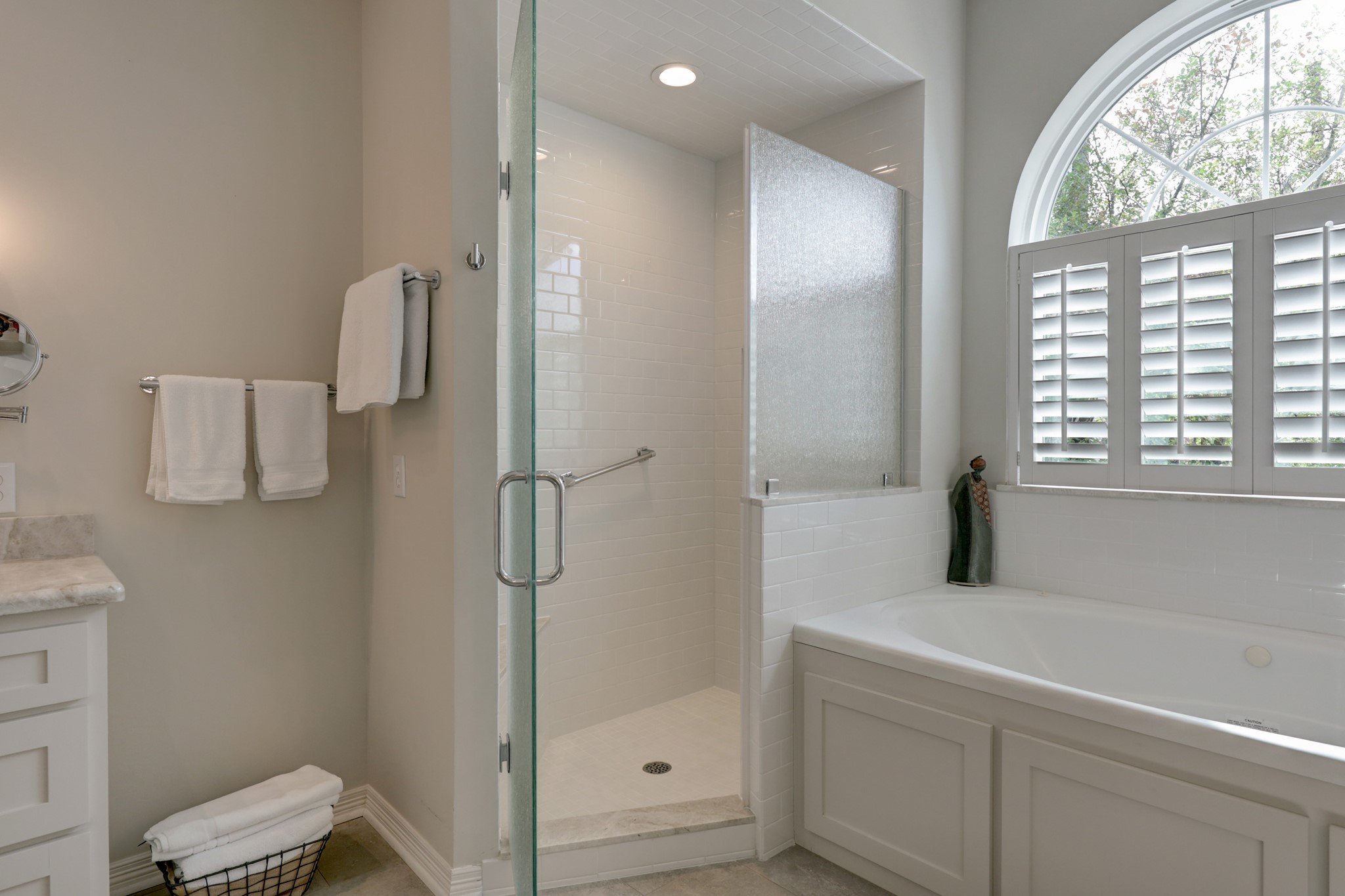 Notice the white subway tile surround and the elegant etched glass in the shower.