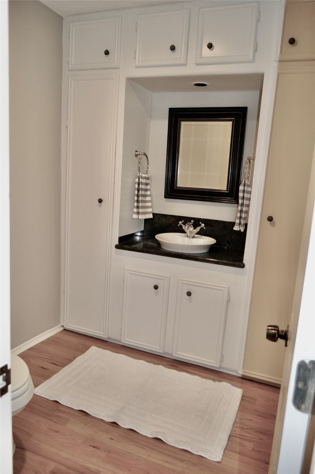 Large powder room with built-in cabinets.
