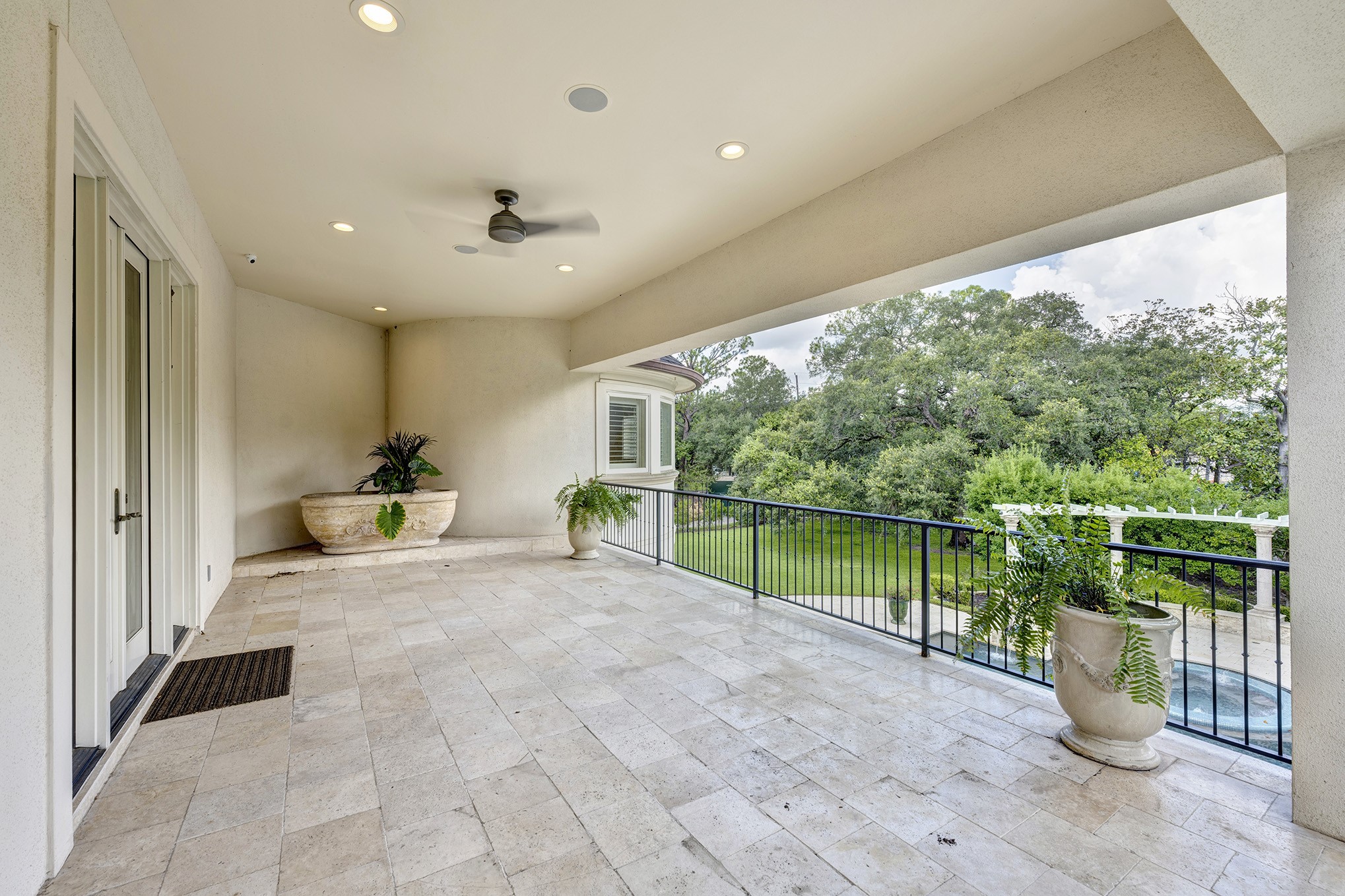 Covered balcony off primary suite overlooking pool with curved staircase to pool and yard.