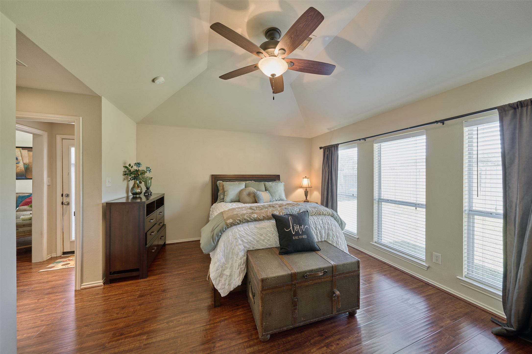 Laminate wood flooring carries from the family room into the primary bedroom. Serene and peaceful the room has a wall of windows and high ceiling.