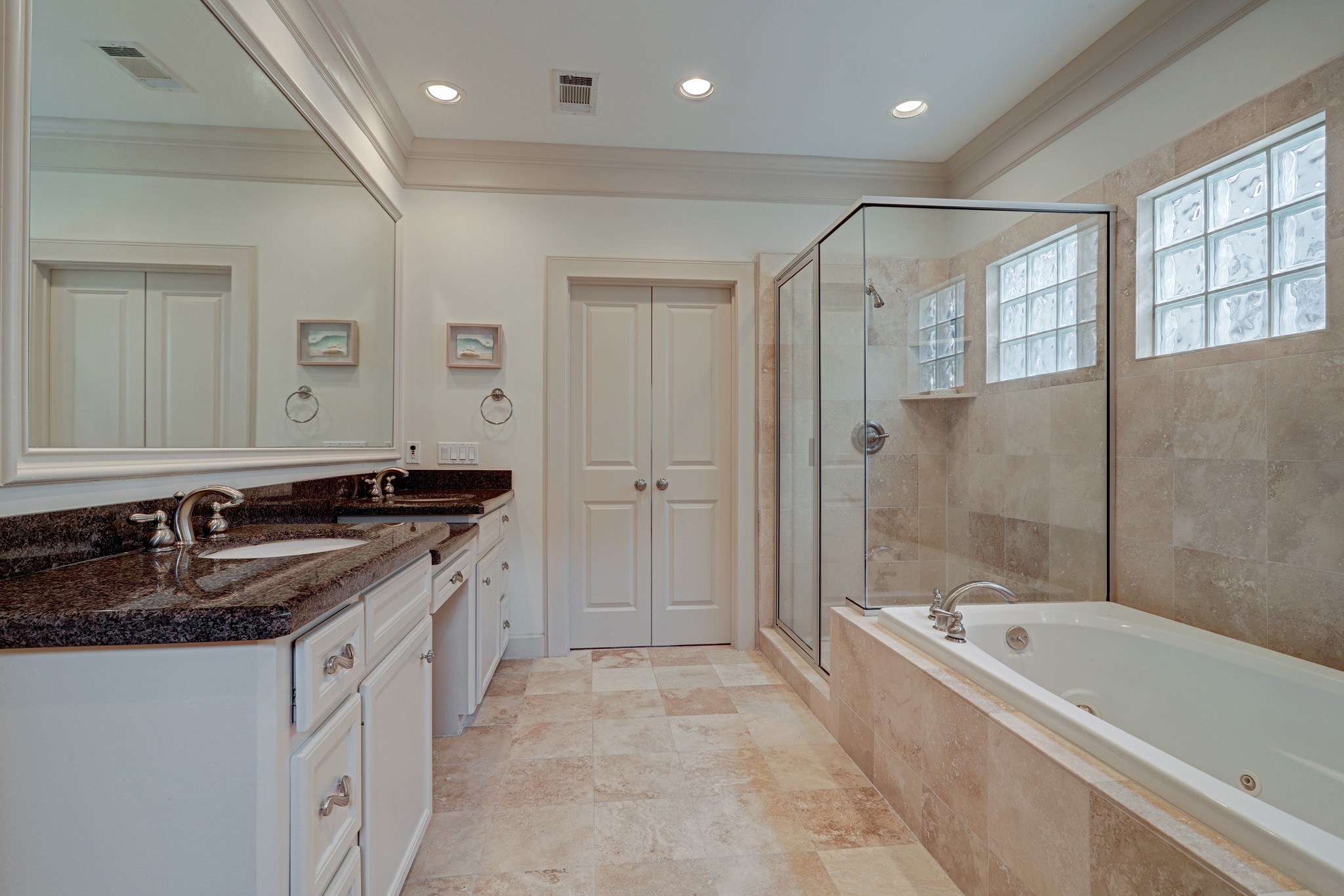 Large primary bathroom has a separate shower and jetted tub, marble floors and counters