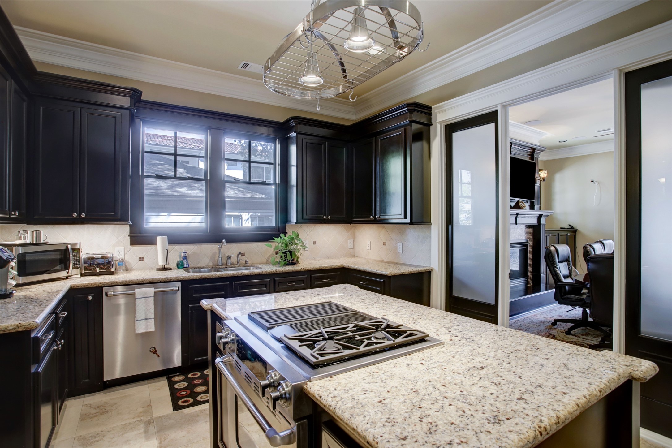 The kitchen features island with granite countertops, gas range, convection oven, & oversized cabinets.