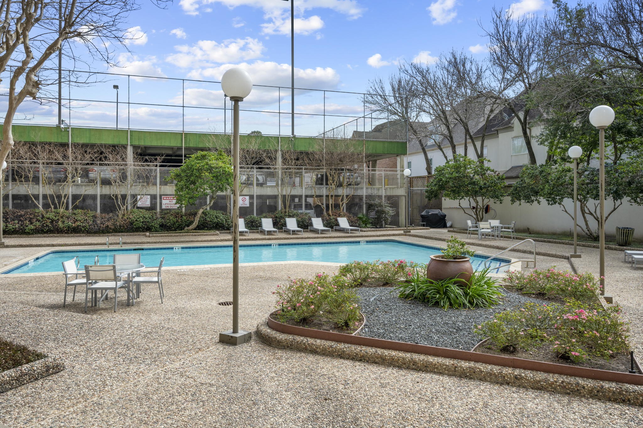 The pool area will make you wish summer lasted year round.  Enjoy plenty of lounging and grilling space!  Visible on the left is the resident parking area with Pickle Ball Court on the rooftop.  Unit 1303 includes 2 prime 1st floor reserved parking spots.