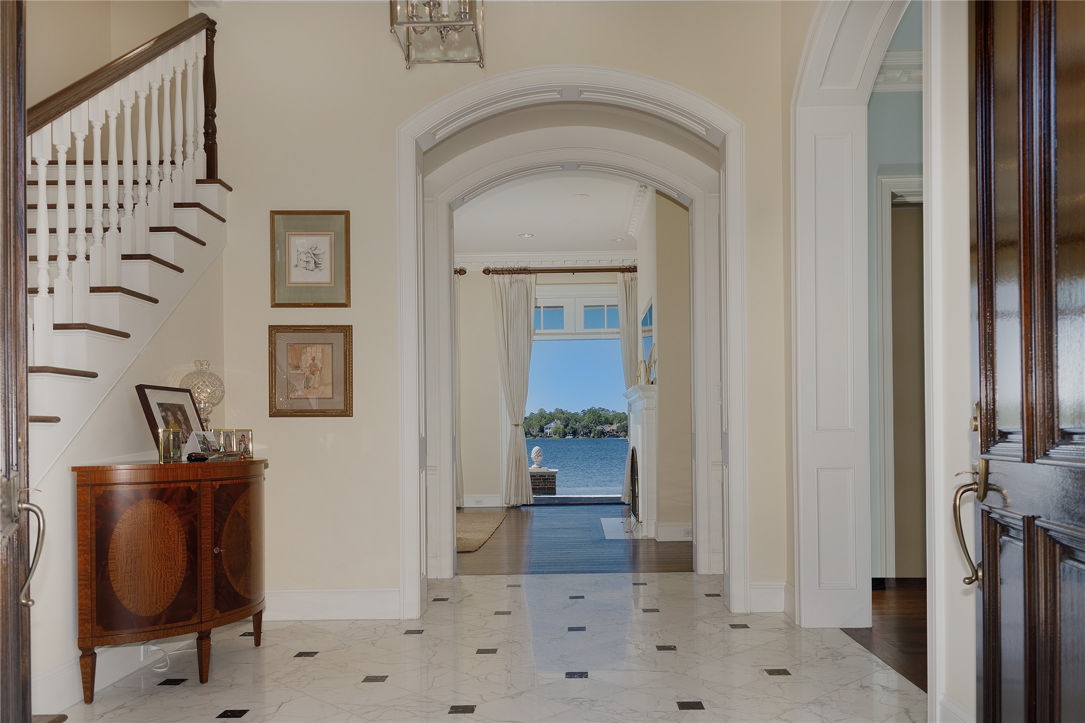 The lake view continues through the Calacatta Oro Marble foyer and the view is beautifully framed by paneled arches.