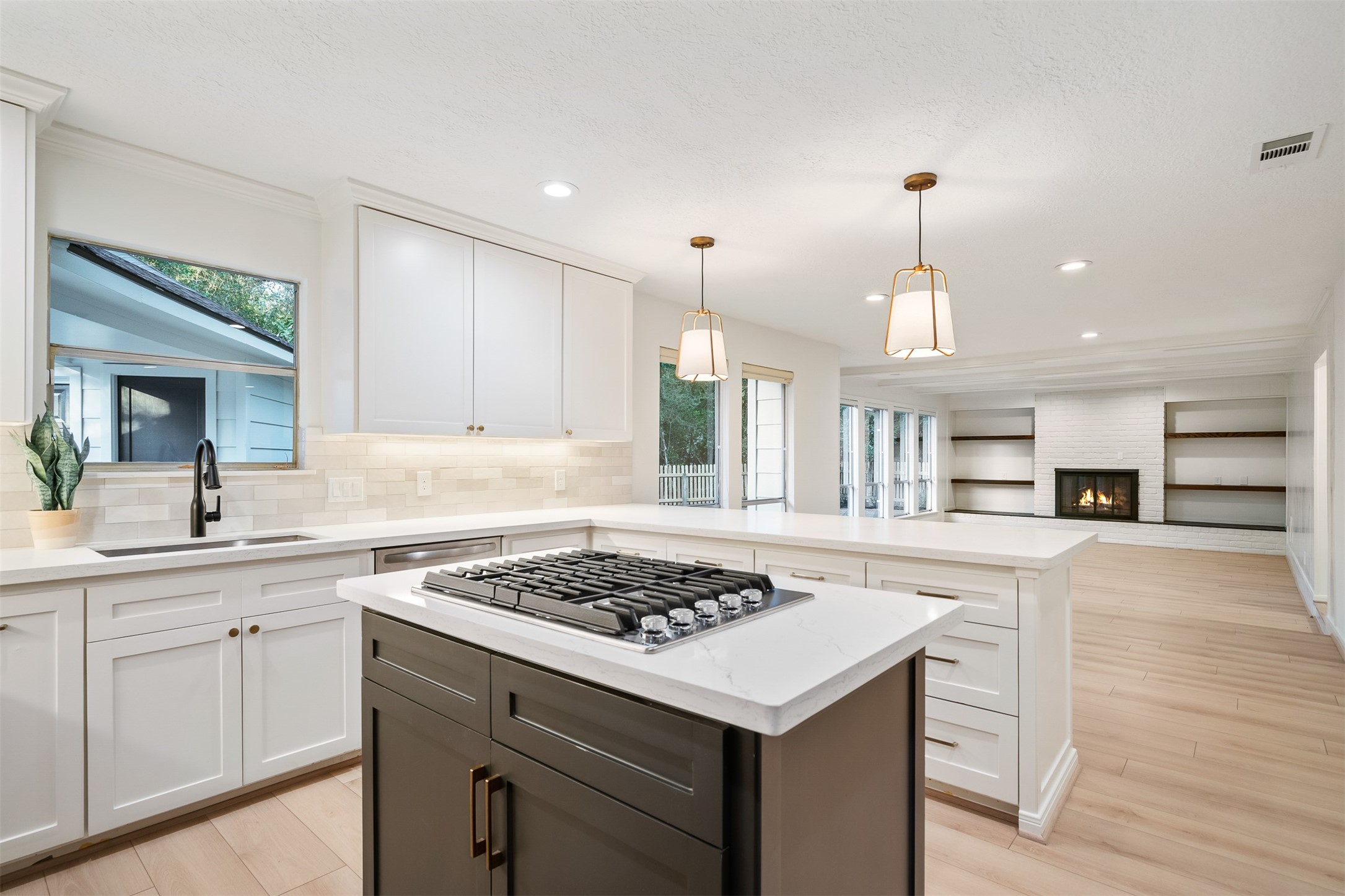 Stunningly remodeled kitchen with gas cooktop, electric oven, quartz countertops and ceramic backsplash.