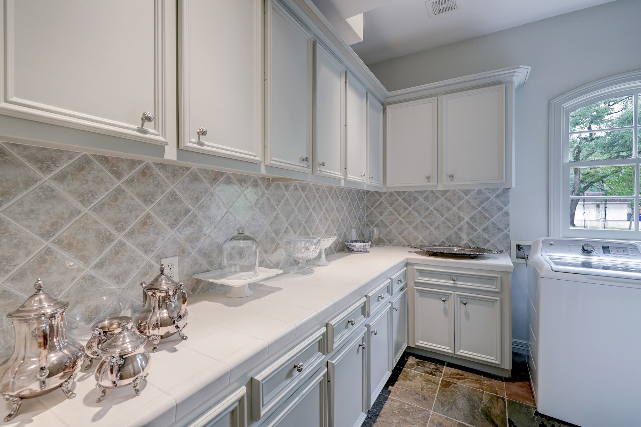 Utility room with storage off of butler's pantry easily serves as storage overflow, or catering space. An appliance nook is discreetly tucked away.