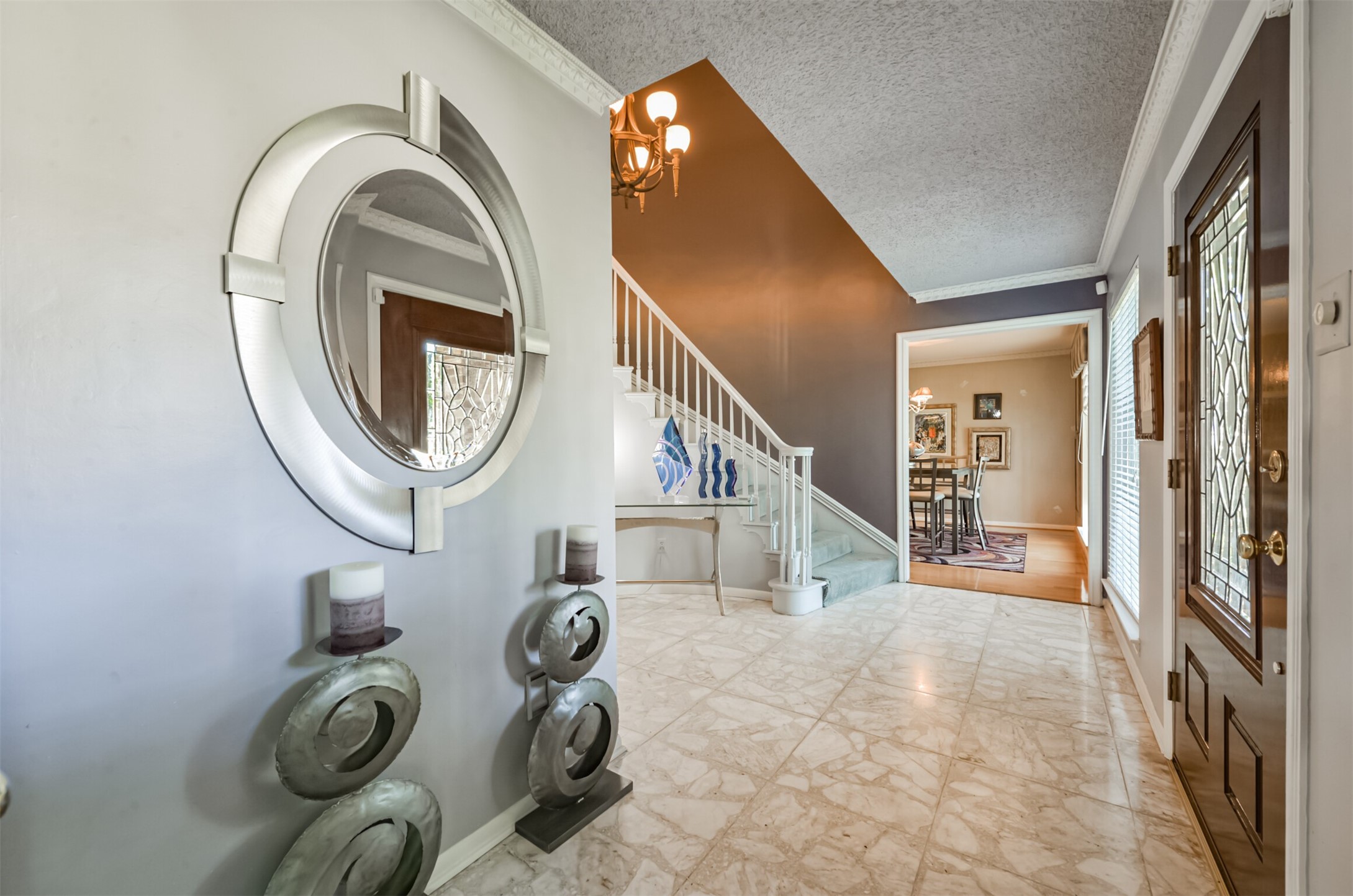 The dining room can be seen through the doors by the stairs. This entry is truly grand and makes a statement about the colorful decorative style of the current owners.