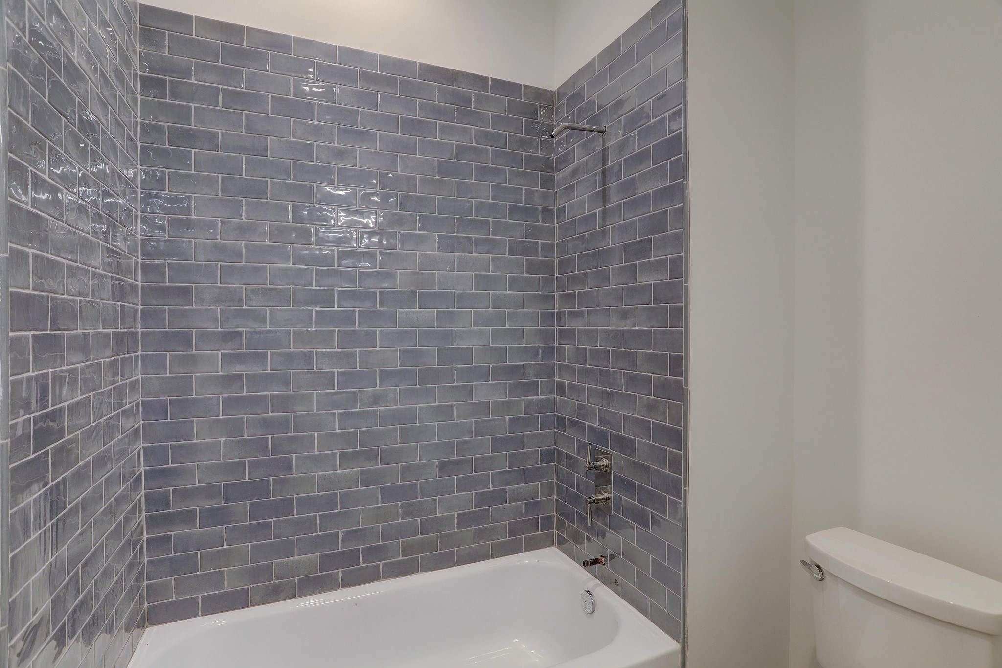 Handmade Italian Misty blue subway tile compliments the tiled floor in the en suite guest bath off the guestroom with the treetop balcony.