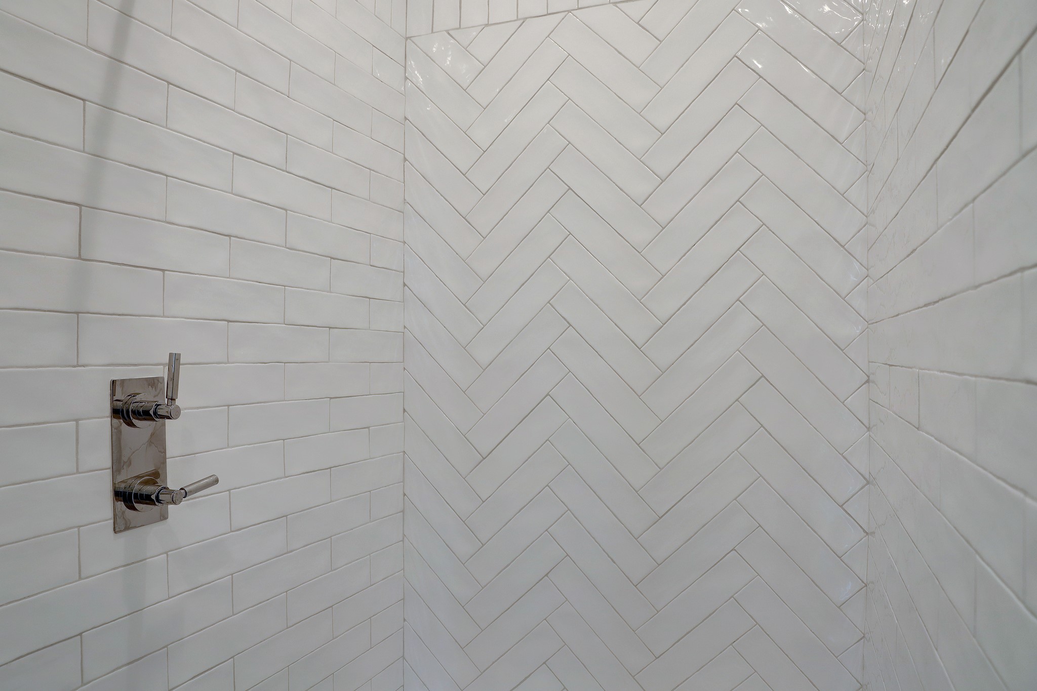 Third floor shower with herringbone patterened tile.