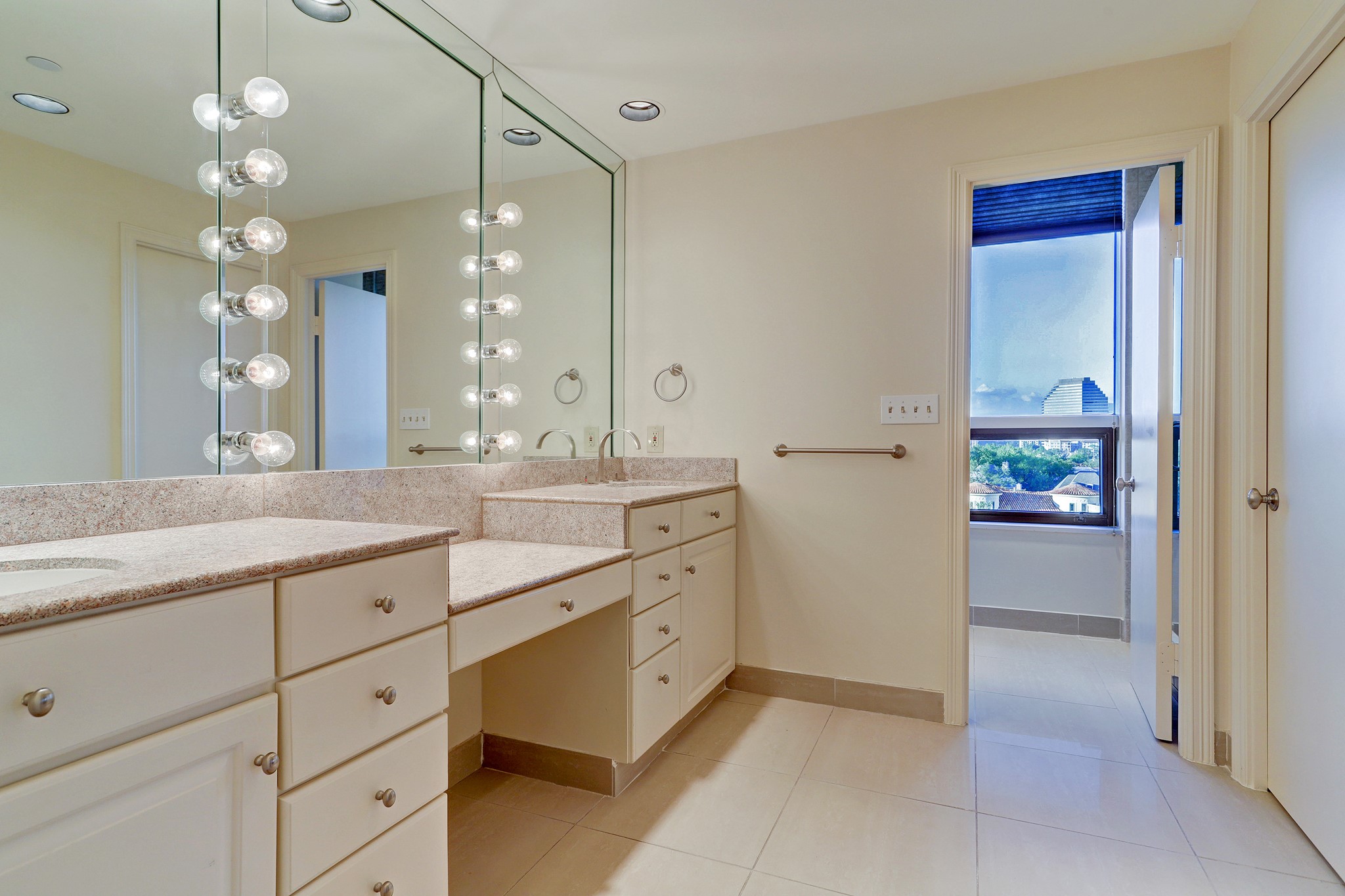 Remodeled bathroom with double sinks and vanity. The open door leads to a separate shower and tub and the closed door on the right is a private water closet.