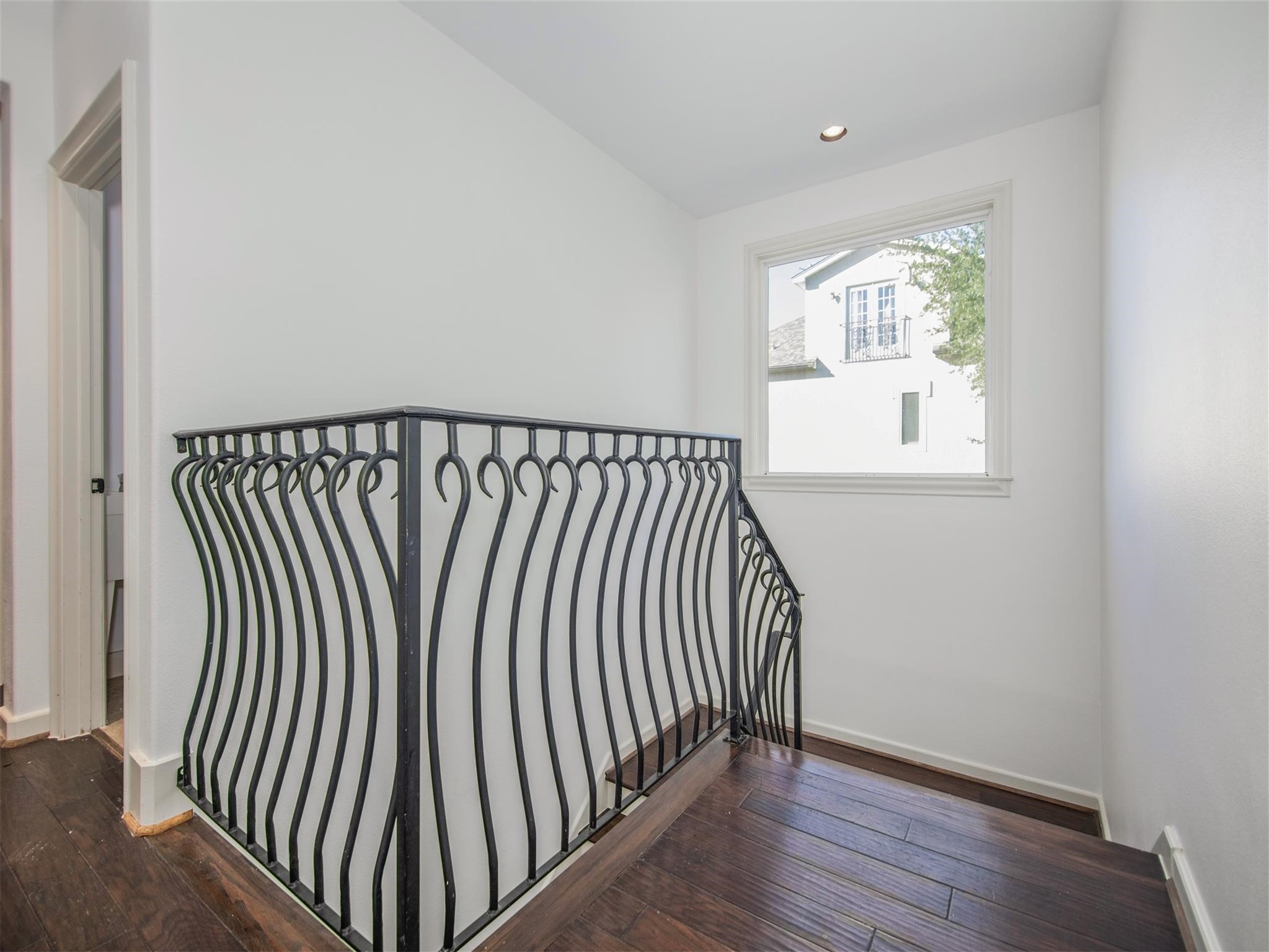 View of custom wrought iron stairwell leading to second floor landing.