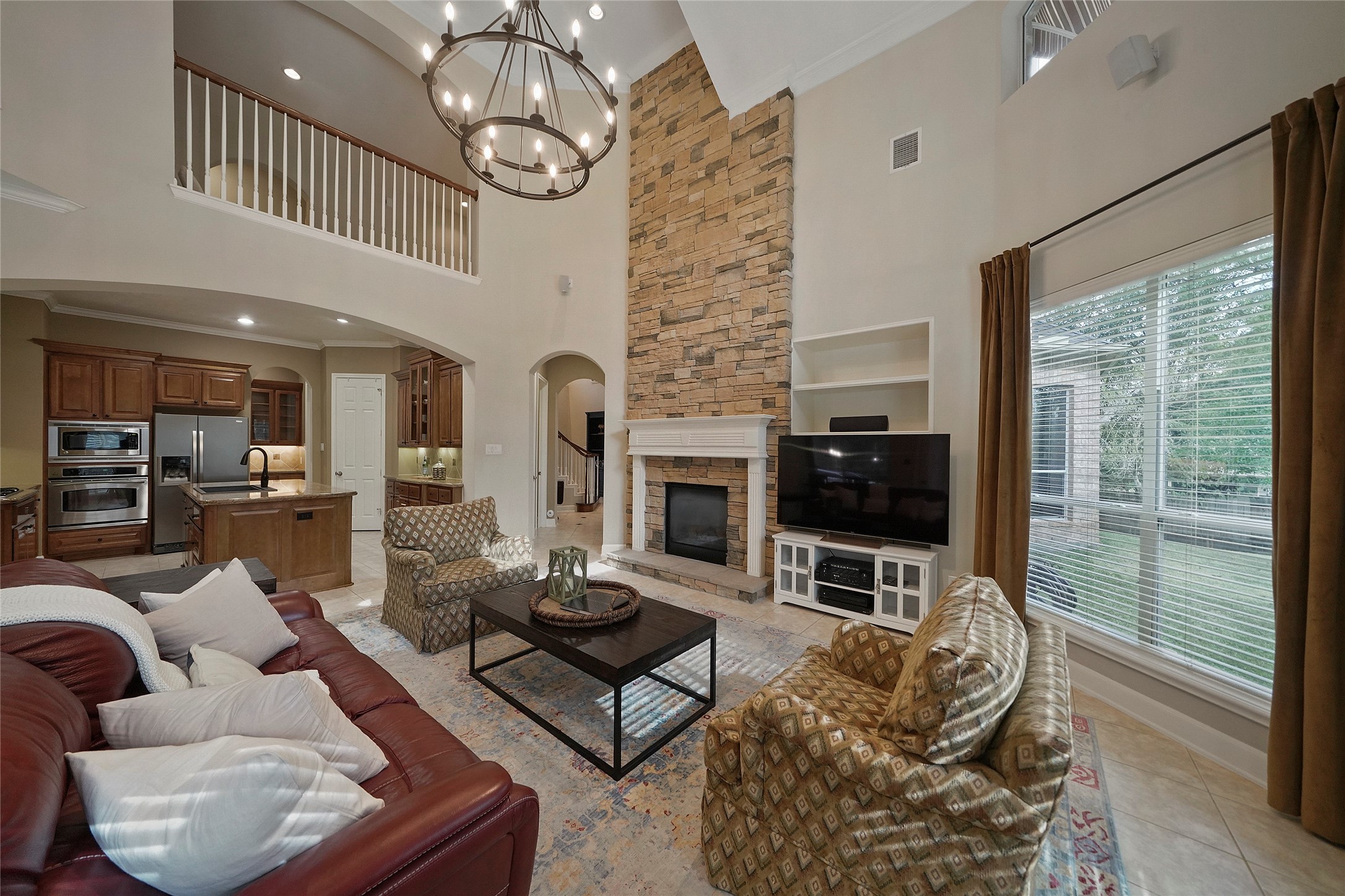 The Formal Living Room overlooks the backyard.  It features a stunning stacked stone, two-sided Fireplace, gorgeous light fixture  and built-in shelving.