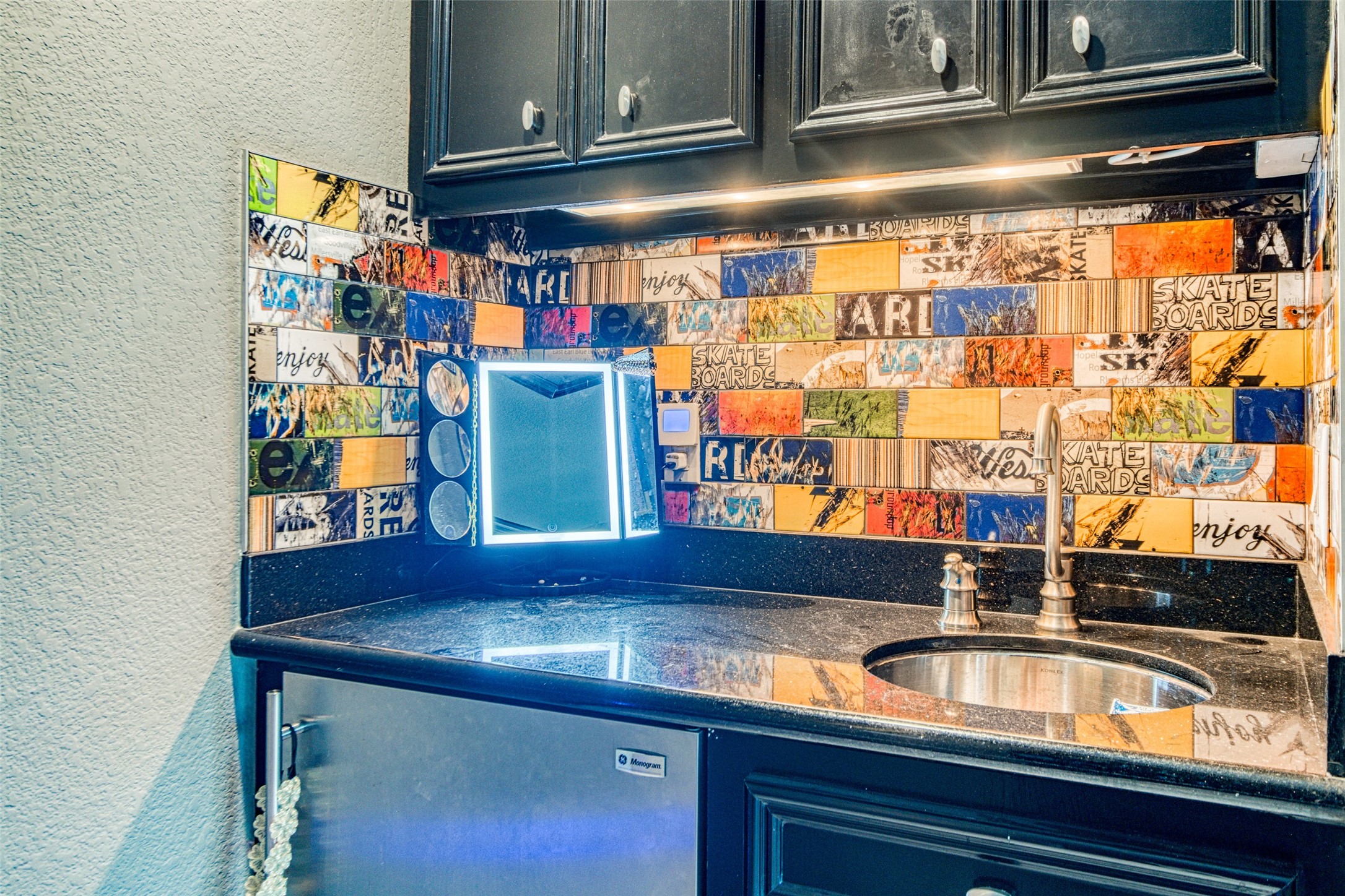 The full wet bar on the fourth floor features custom tile backsplash with graffiti artwork by a noted local artist contrasting beautifully with the granite countertops, beverage cooler, cocktail sink, and plenty of storage for easy entertaining.
