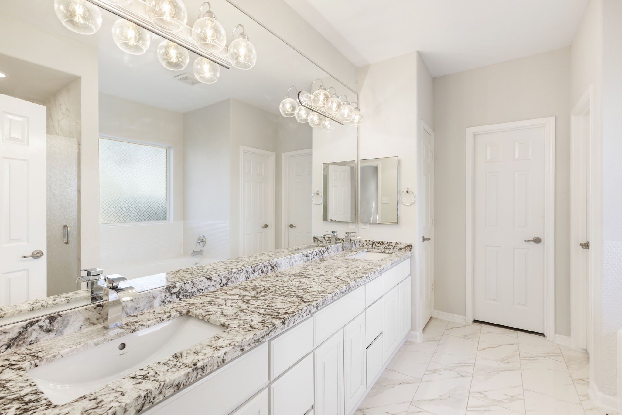The primary bath offers double sinks with polished faucets. granite counters and upscale lighting.