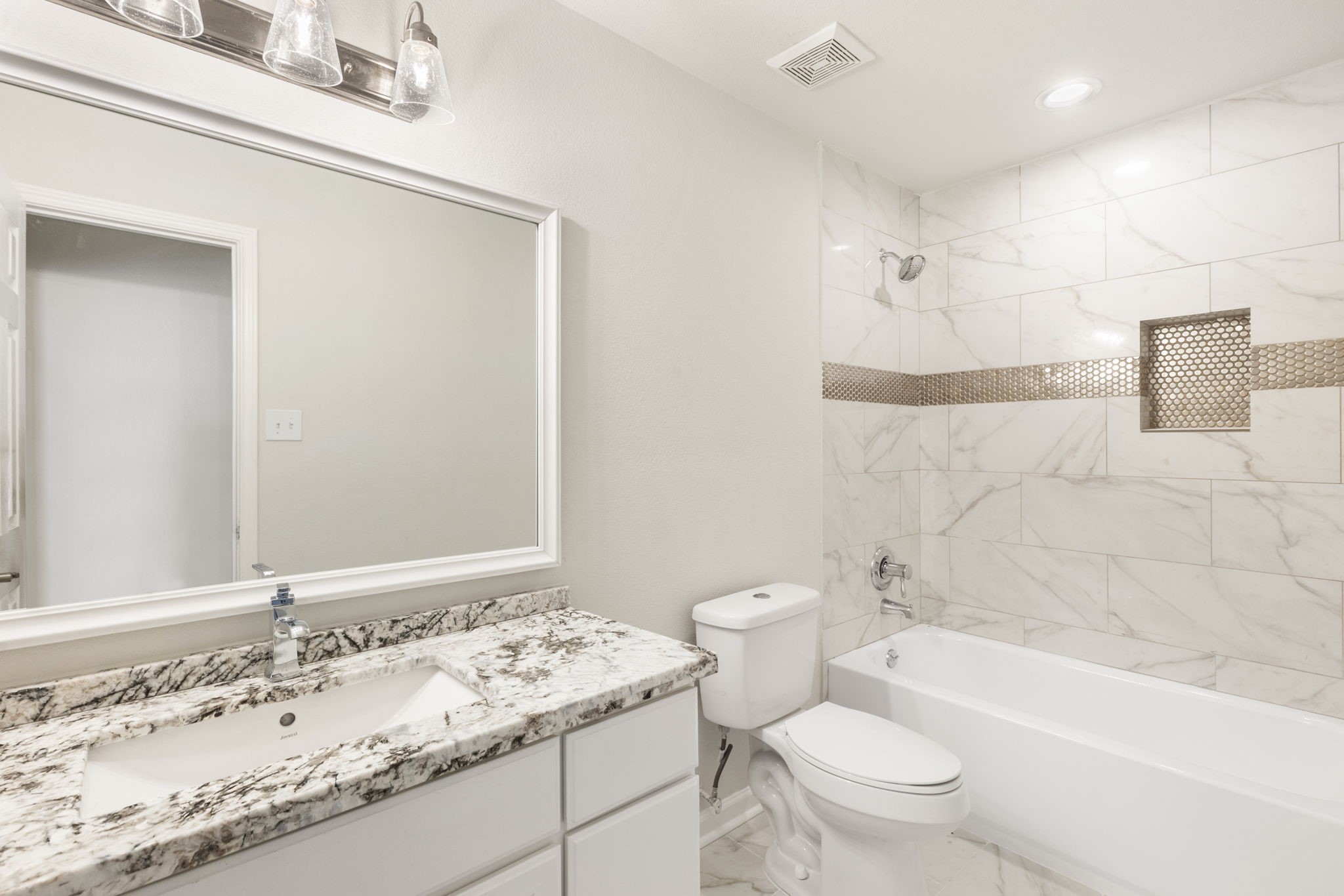 The full bath has access from the hall and is situated between two secondary bedrooms. The bathroom boasts granite counters, white cabinetry, framed mirror, shower/tub combination with tile surround.