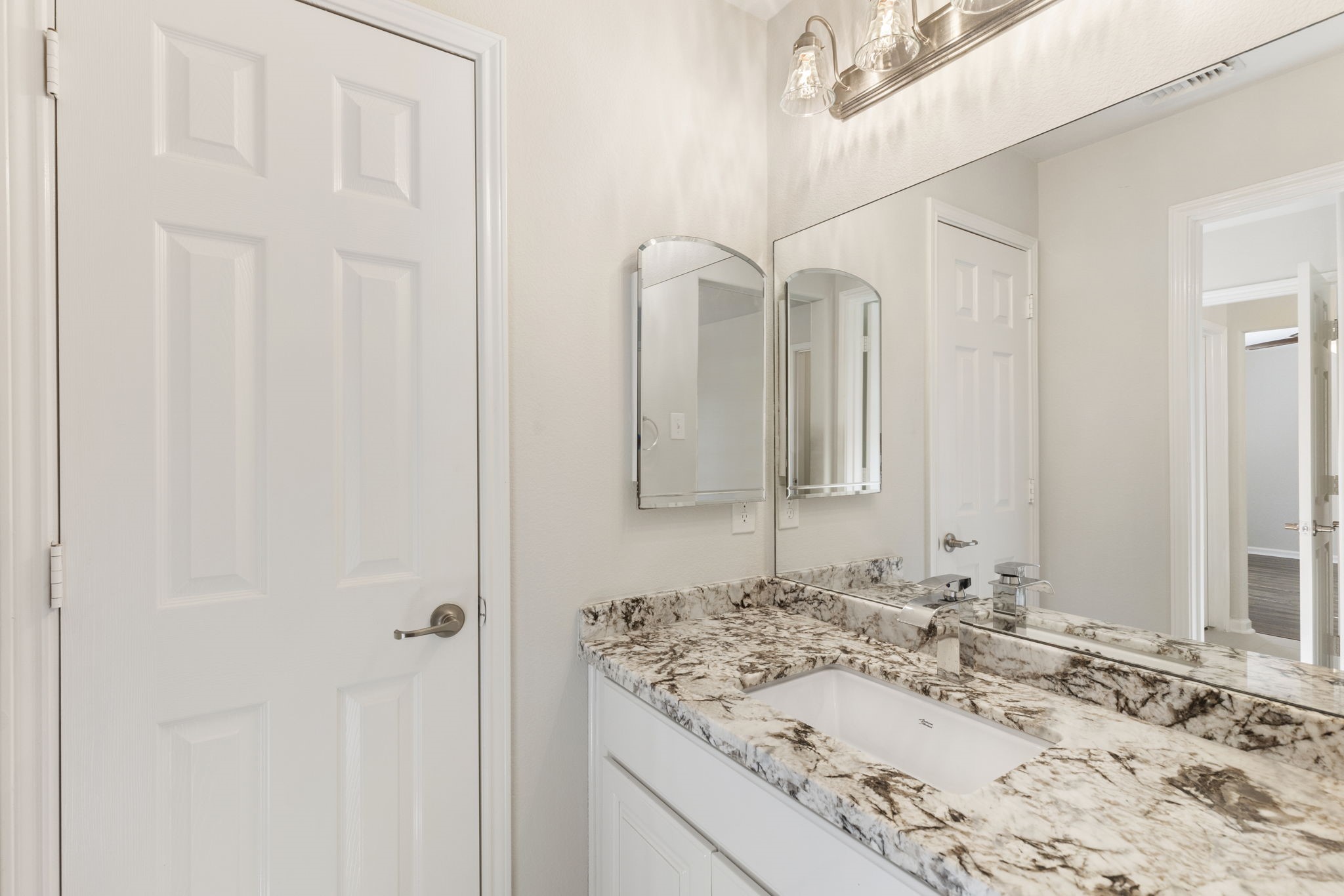 The other secondary bedroom's jack and jill bath has coordinating granite counters and updated lighting and plumbing fixtures.