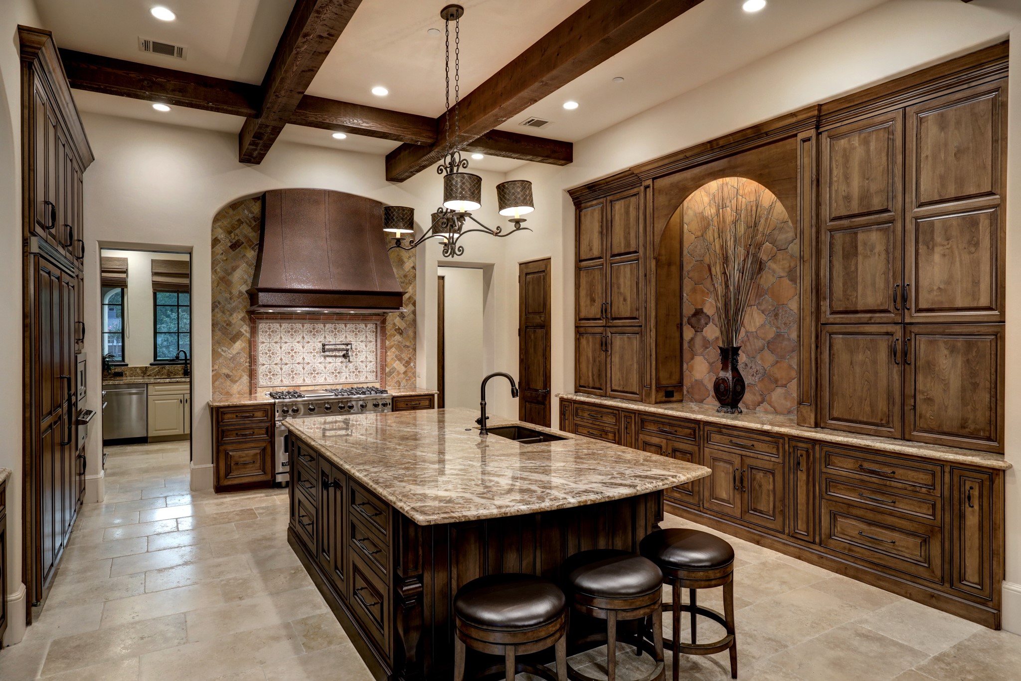 Custom wooden cabinetry, copper hooded air vent and rich detailed brick & tile work