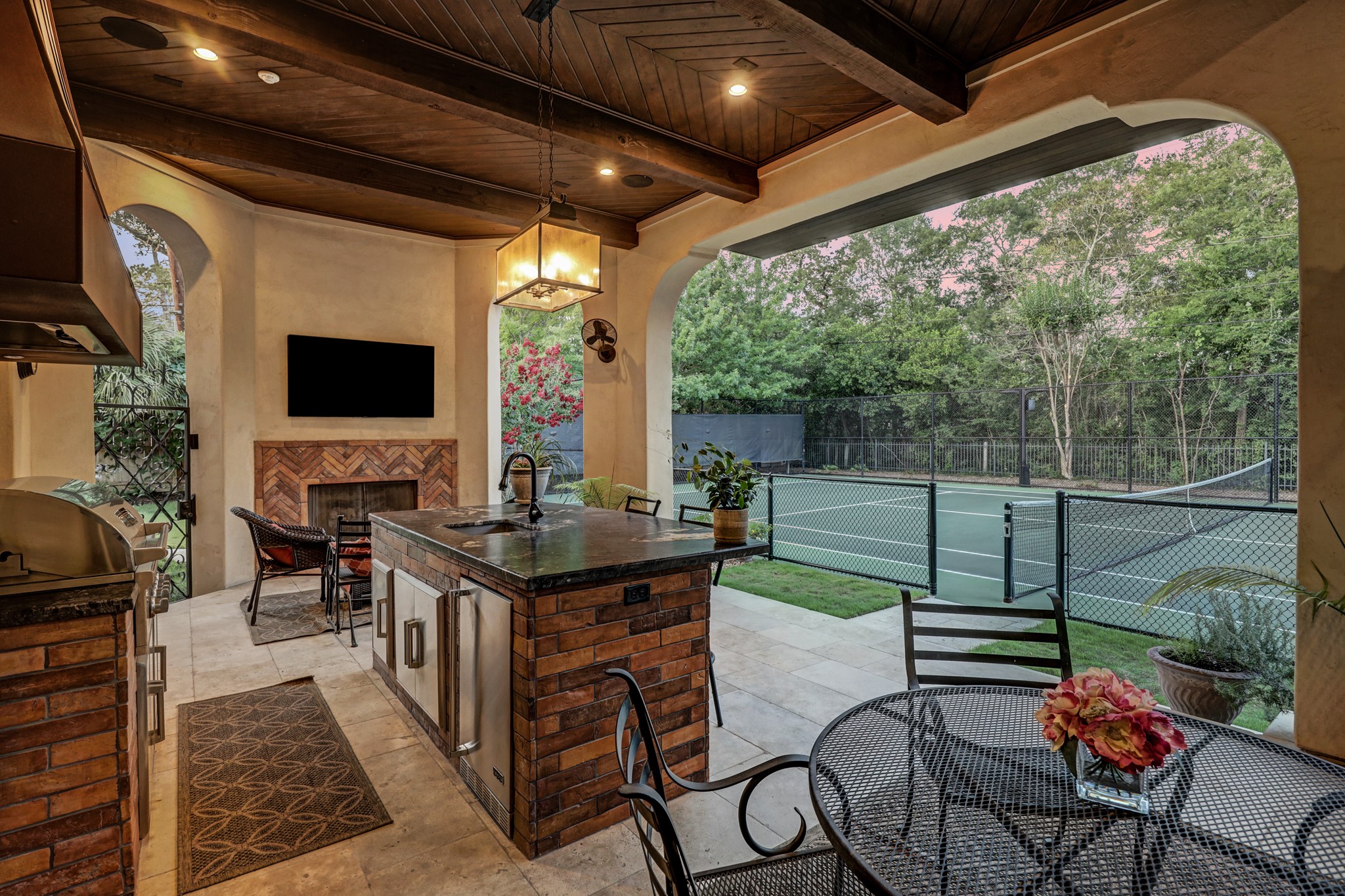 Resort-style outdoor entertainers space includes the fully equipped summer kitchen, fireplace and facing tennis court