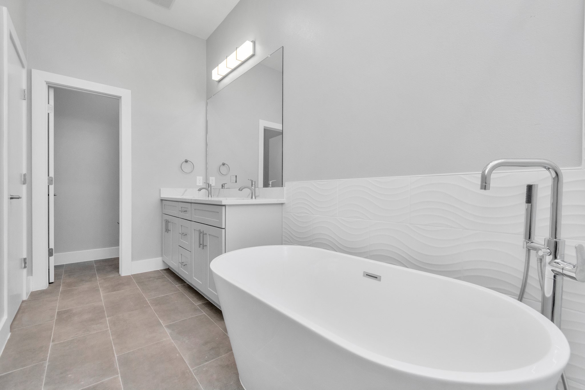 Styled with modern tile behind the tub and grandiose fixtures!