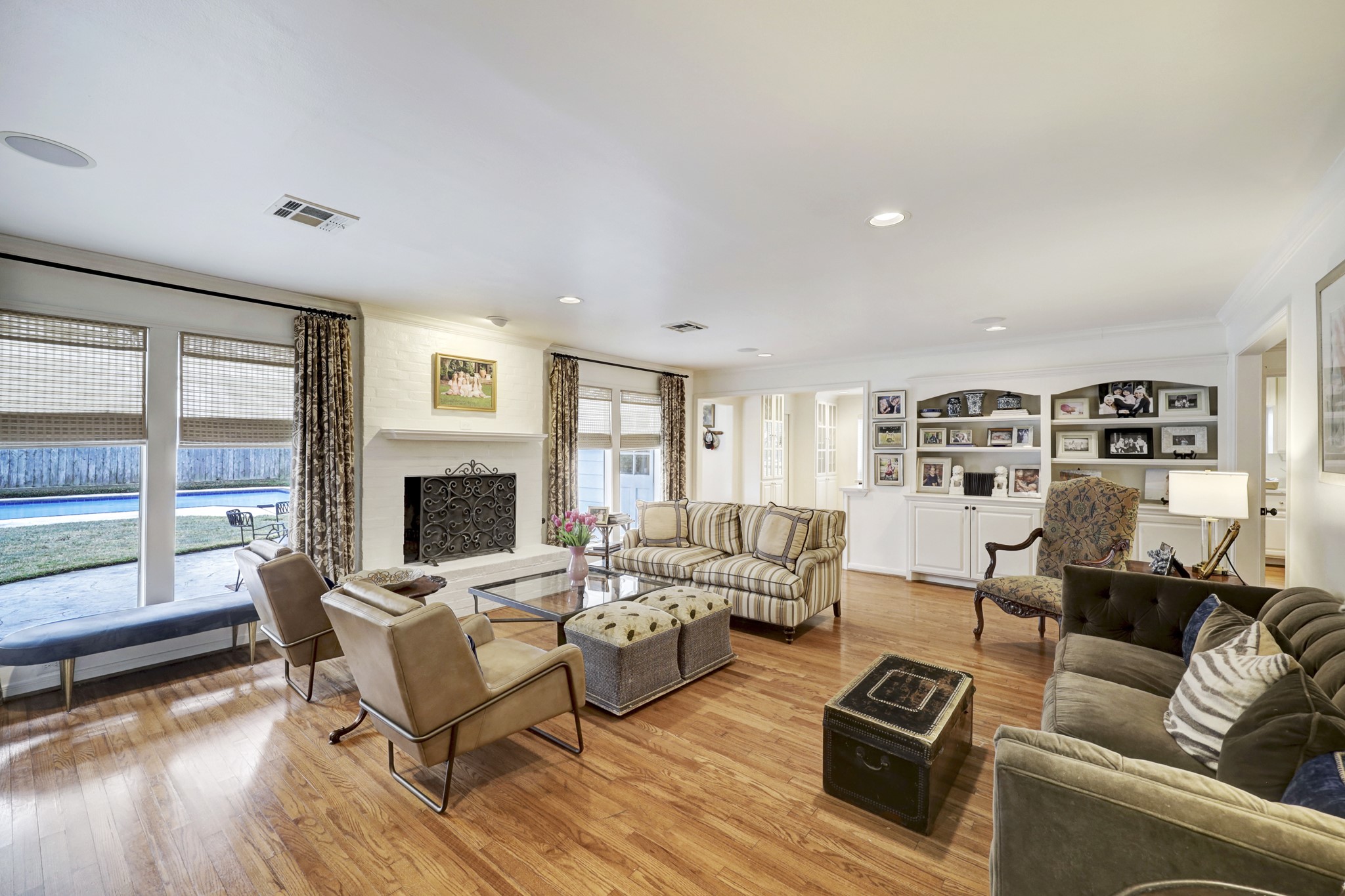 The family room surrounds a wood burning fireplace and boasts windows on either side overlooking the pool.