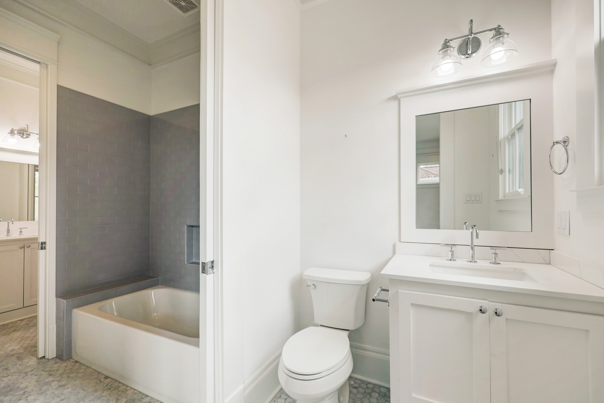 The Jack-and-Jill bathroom includes separate vanity and commode areas for each bedroom, with pocket doors that open to a large tub/shower. Tile flooring, quartz counter and polished nickel fixtures run throughout.