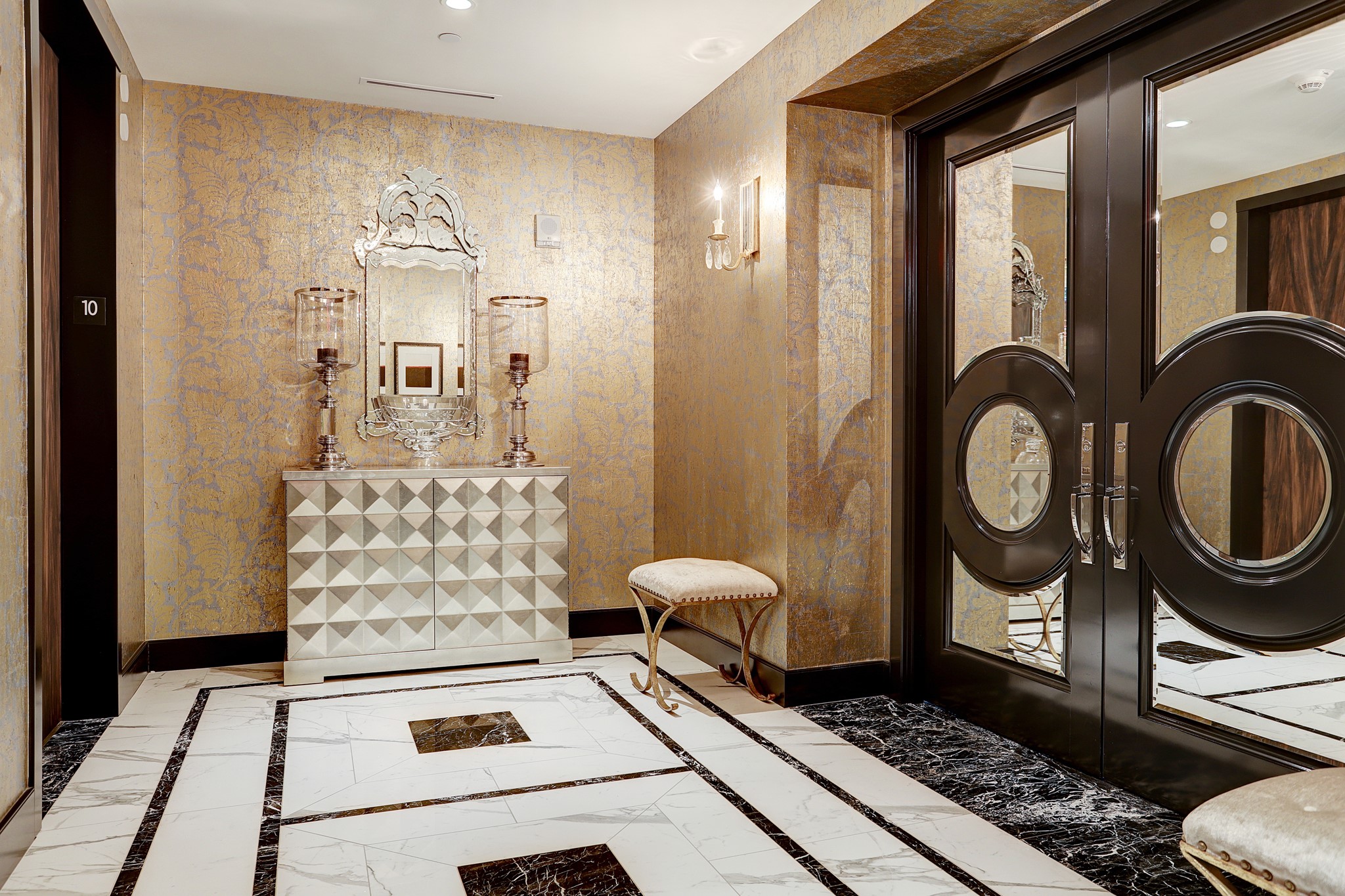 Your own private elevator lobby with custom wallpaper, porcelain tile floors with marble border and accents, and double door entry into the unit.