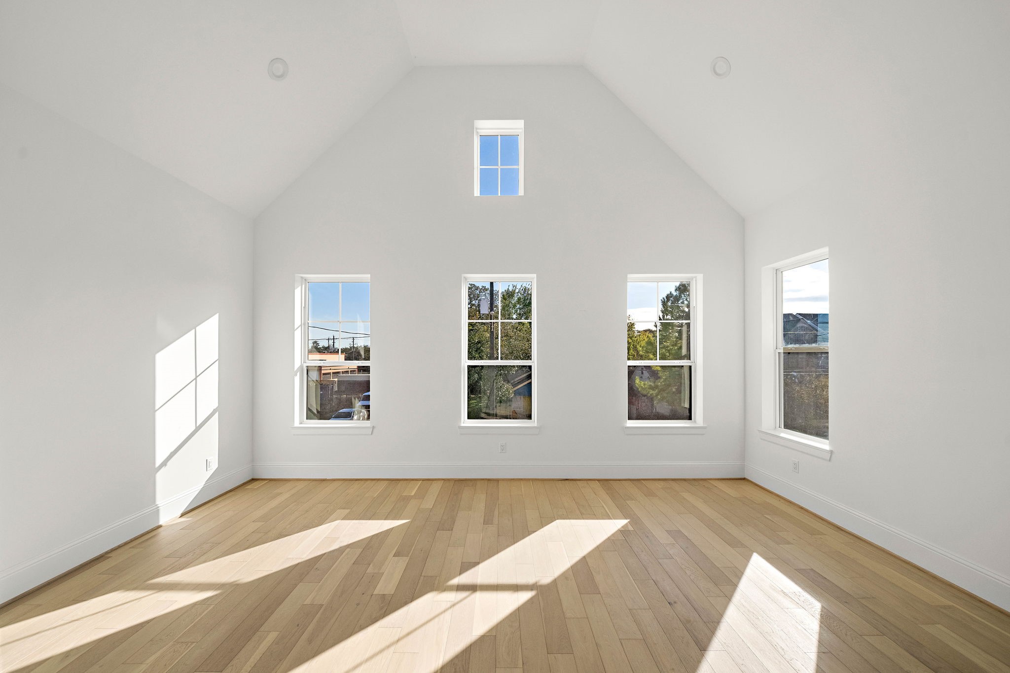 Generously-sized master suite with an abundance of windows, vaulted ceiling, and beautiful wide plank wood flooring. (Photo is of a completed home, finishes are subject to change.)
