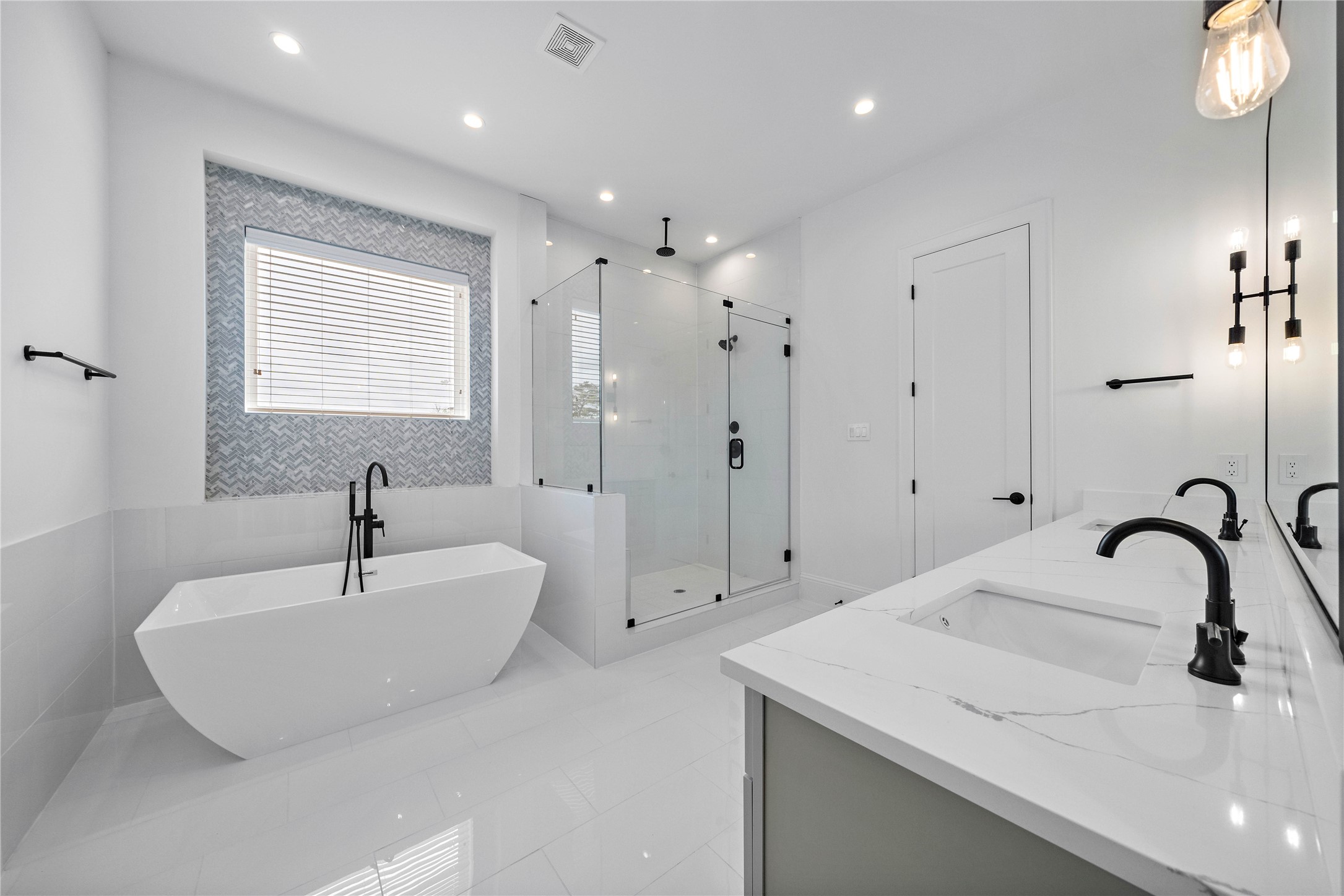 Spa-like master bath features frameless glass shower enclosure with dual shower heads and decorative tile with Herringbone inset design. Freestanding soaking tub for those relaxing evenings. (Photo is of a completed home, finishes are subject to change.)