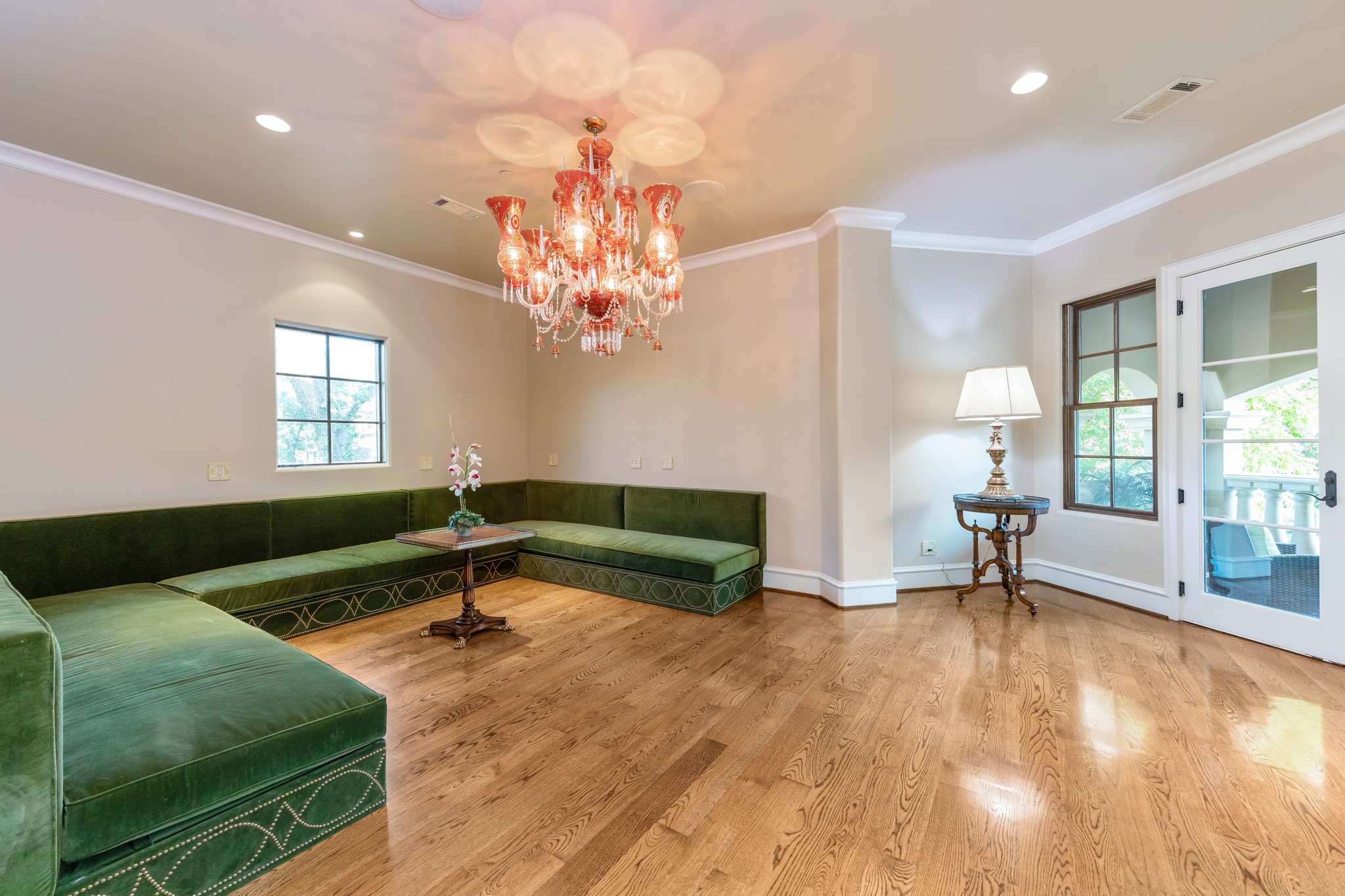 Custom ornate carved wood doors lead into this fun multi purpose party room that boasts luxurious custom designed built-in banquette sofa seating with green velvet cushions. Another set of french doors opens to a covered balcony with decorative stained wood and 42” baluster railing.